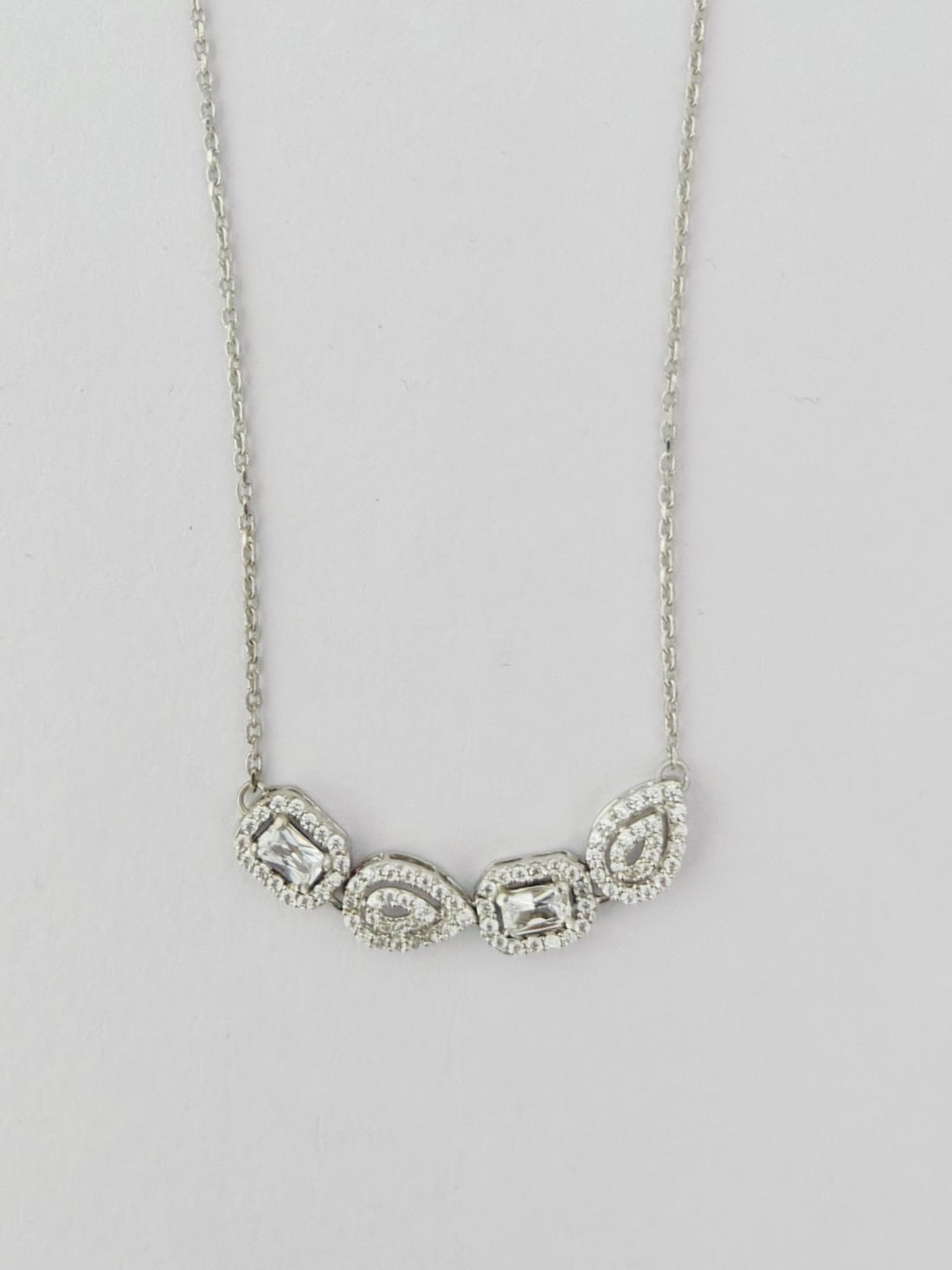 Silver necklace with three teardrop-shaped pendants on a light gray background