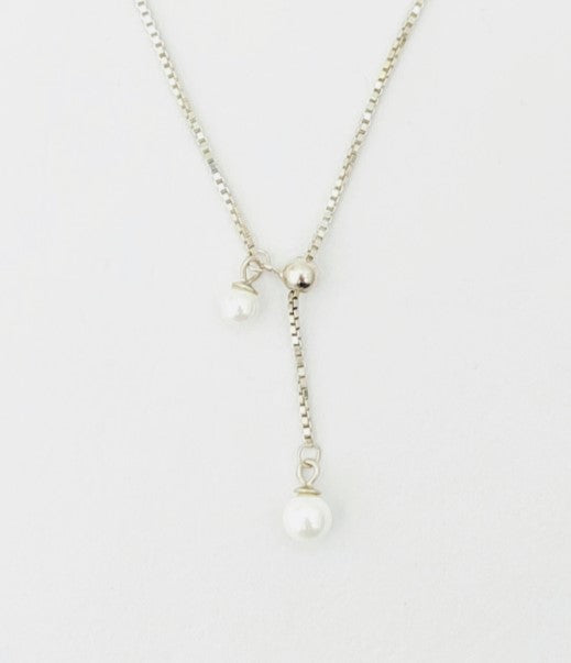 Pearl necklace on a thin chain against a white background