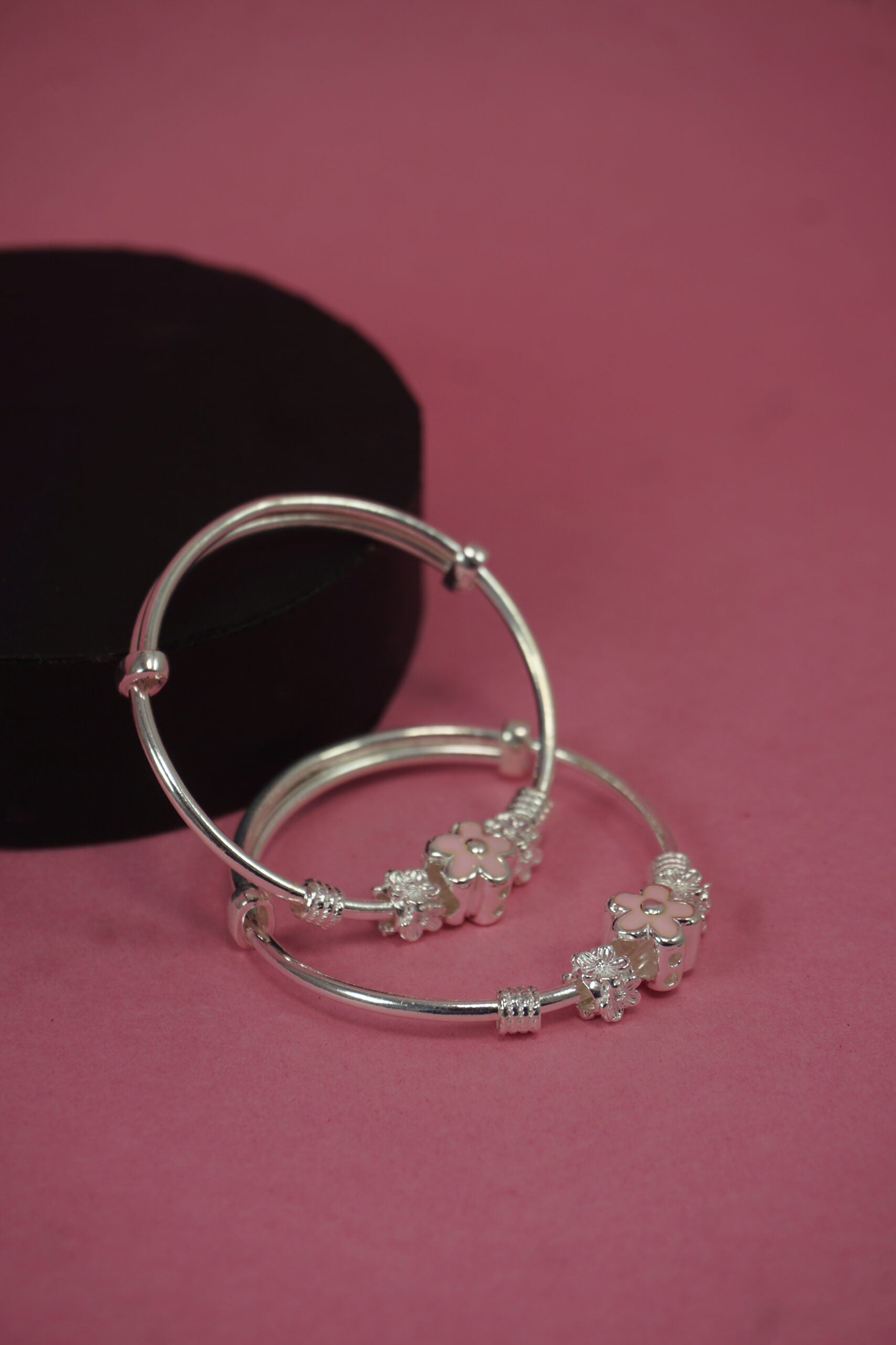 Silver hoop earrings with embedded stones on a pink background