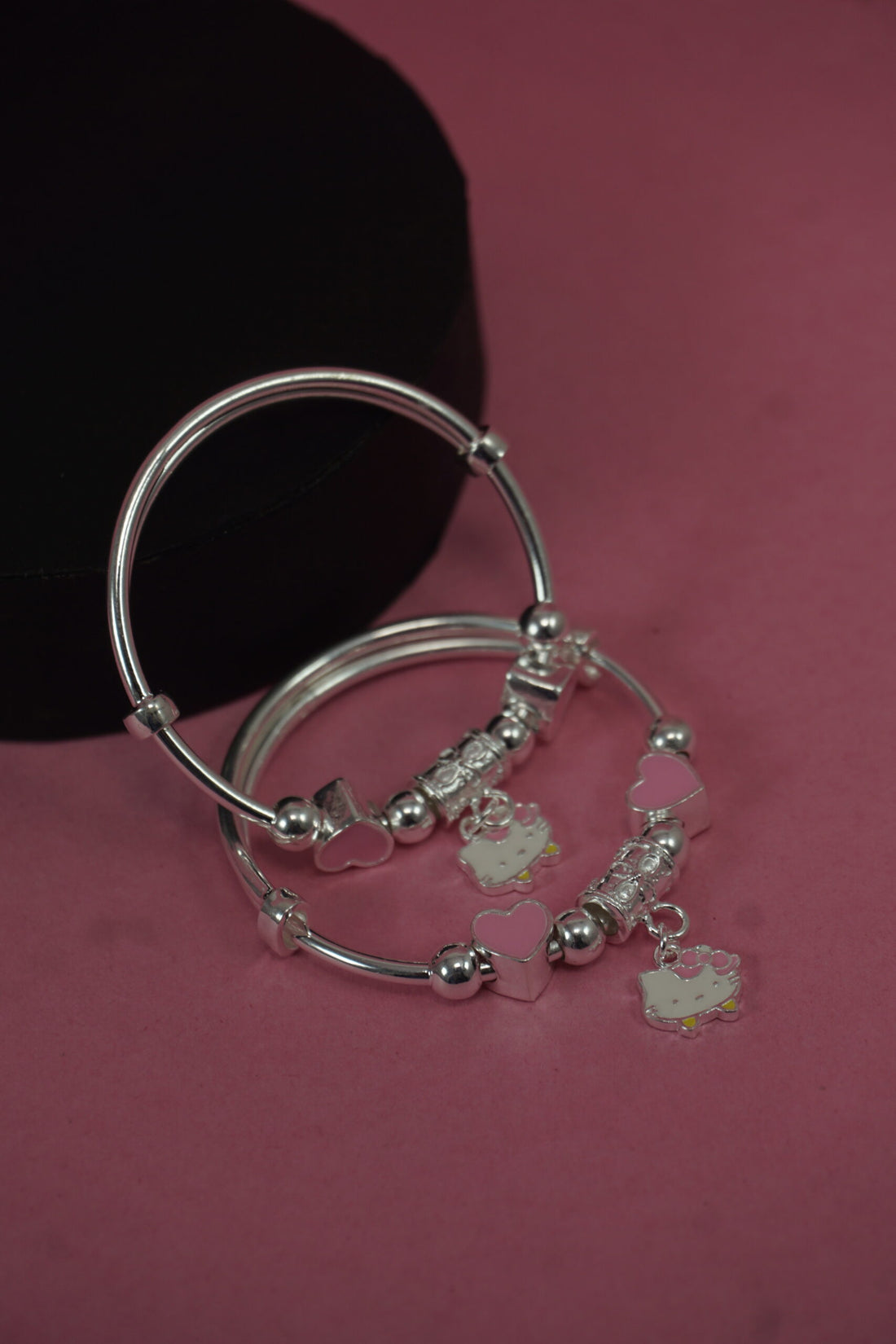 Silver bracelet with charms on a pink background