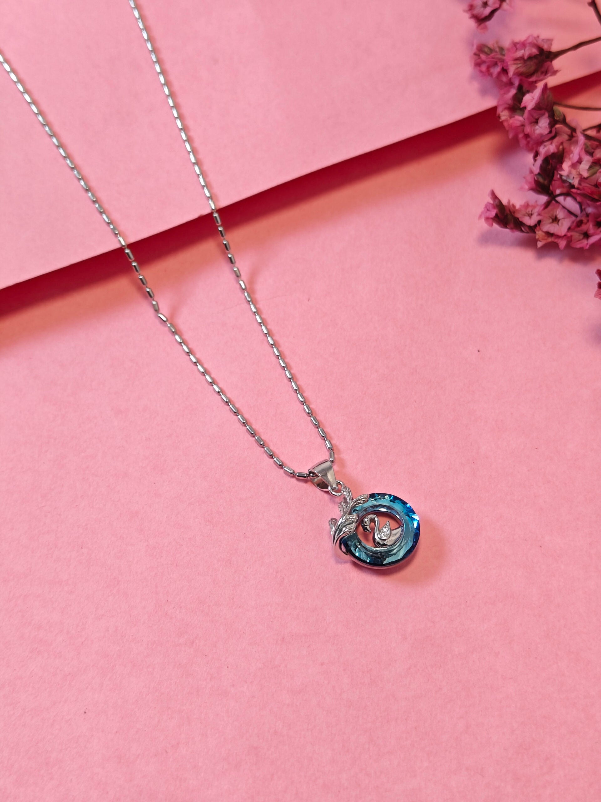 Necklace with a blue pendant on a pink background