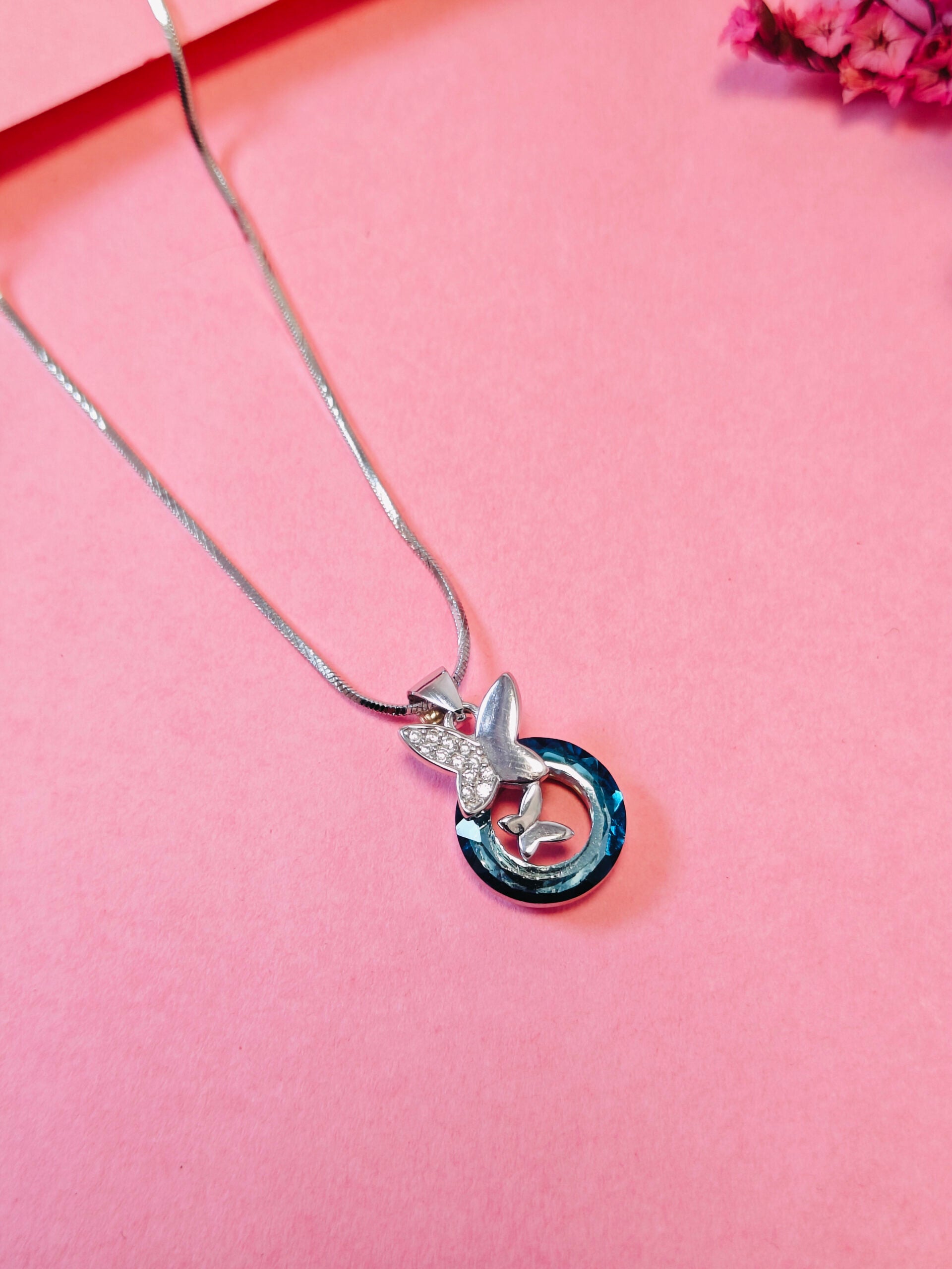 Silver necklace with a unique pendant on a pink background