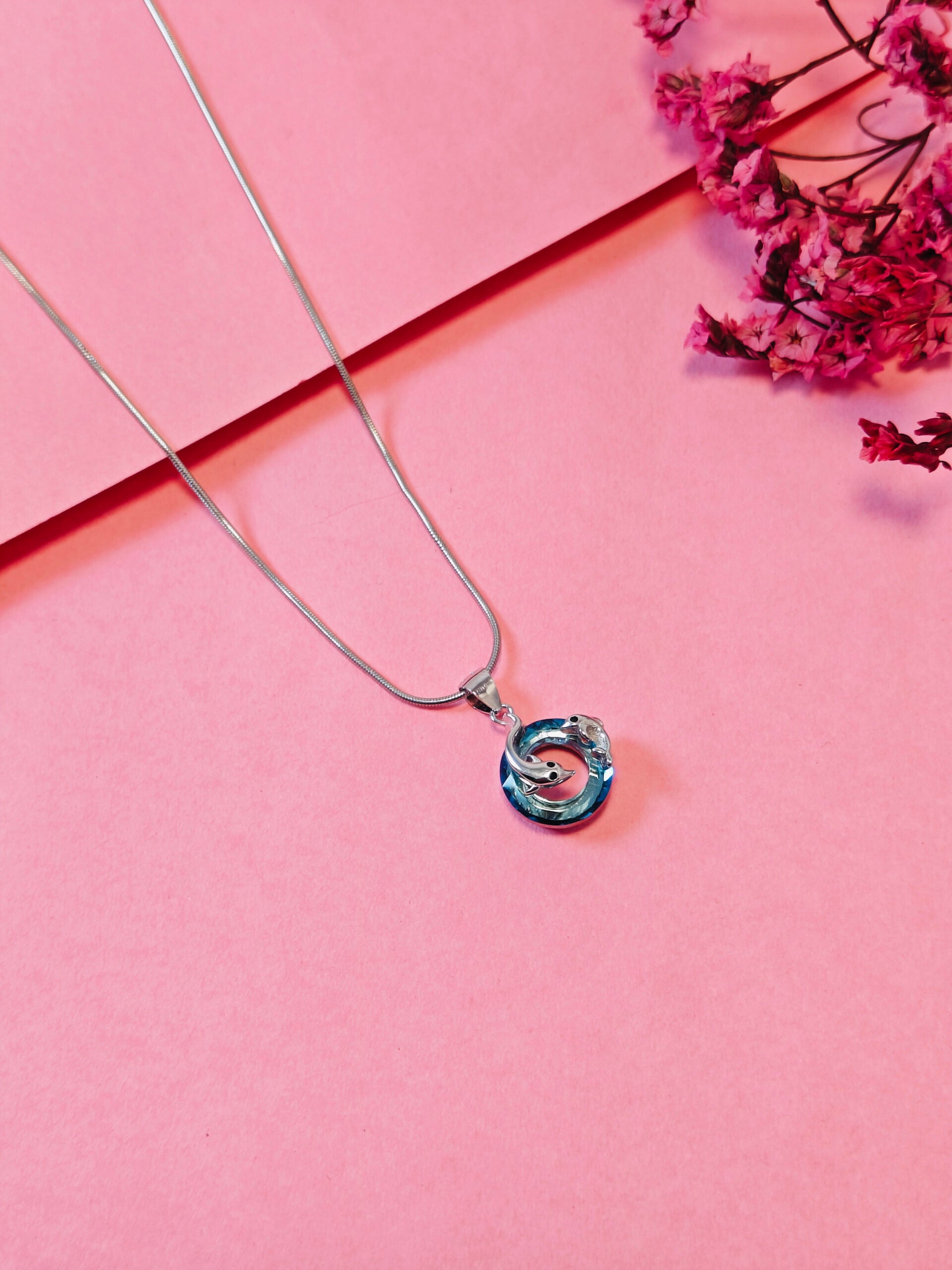 Necklace with a blue pendant on a pink background