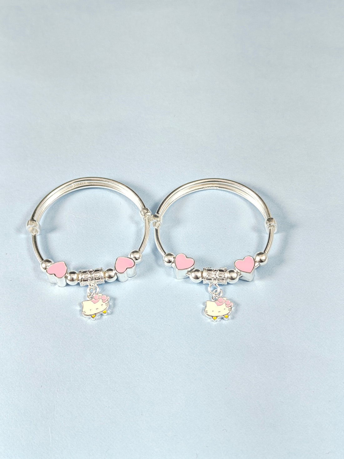 Silver hoop earrings with pink heart charms on a light gray background