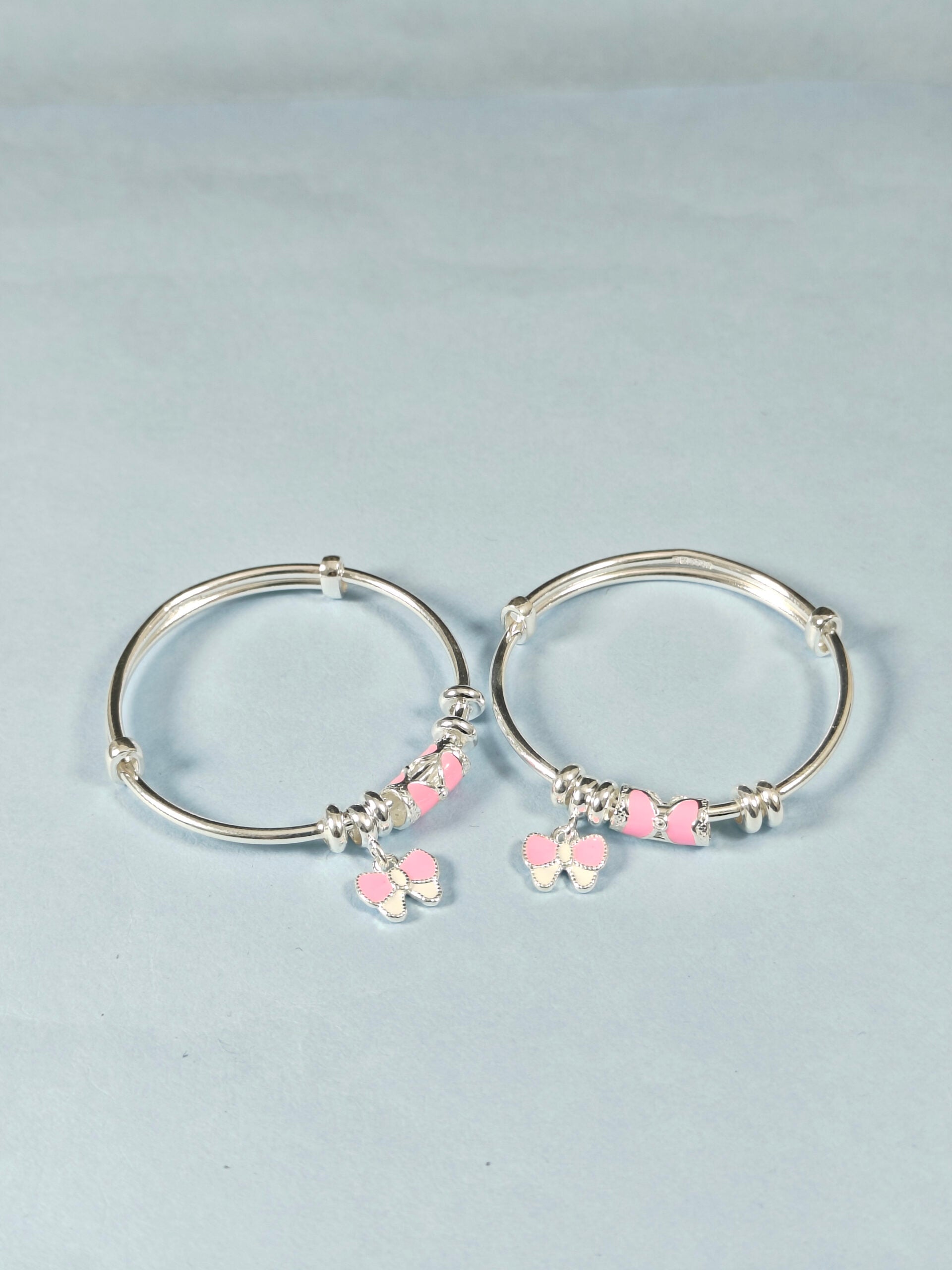 Silver hoop earrings with pink heart charms on a light gray background