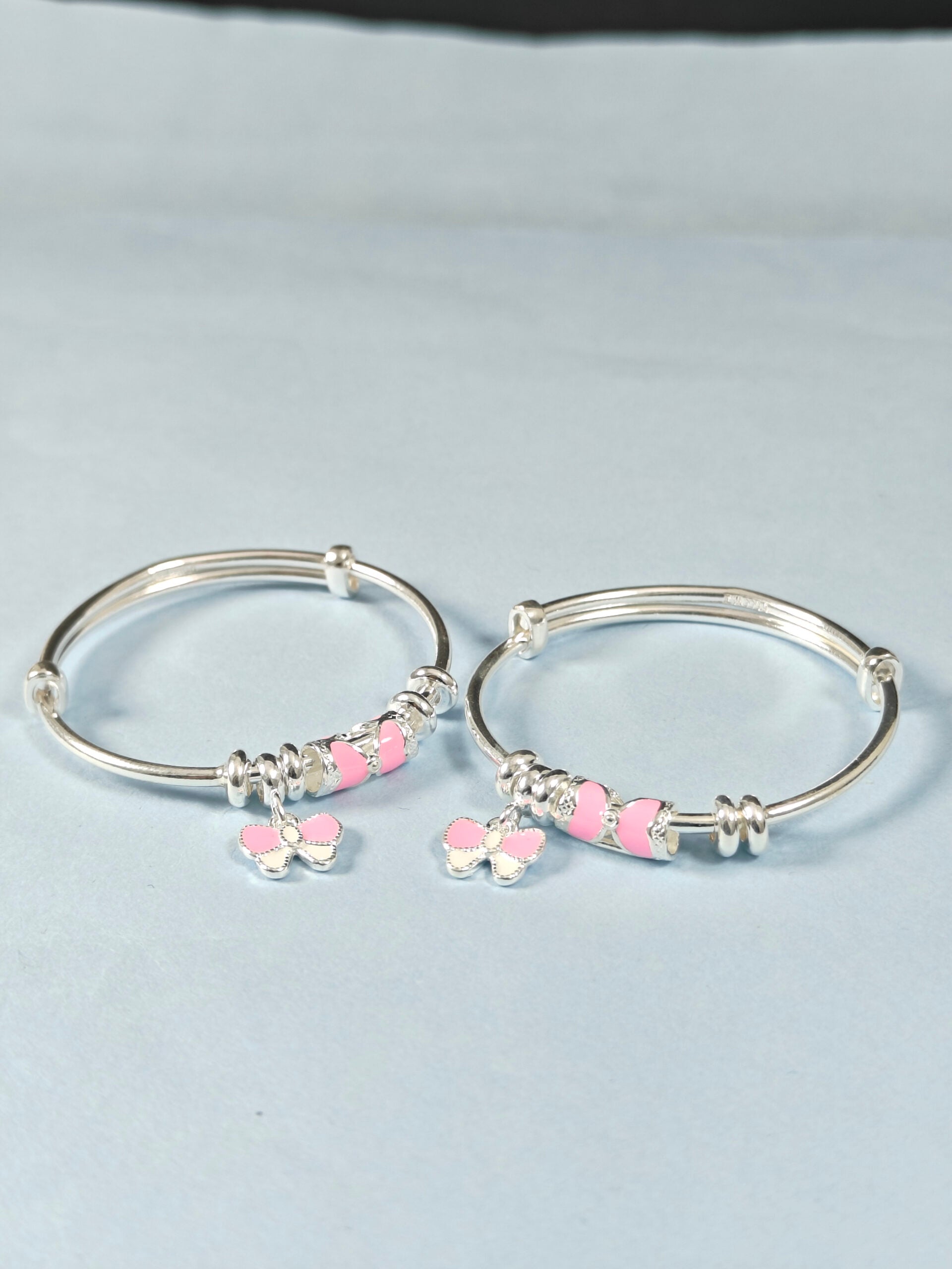 Silver hoop earrings with pink heart-shaped beads on a light gray background