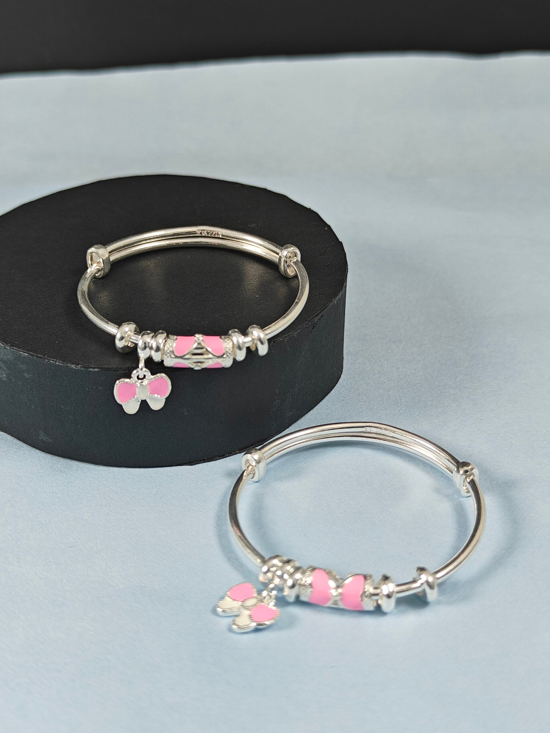 Silver bracelets with pink heart charms on a light blue background