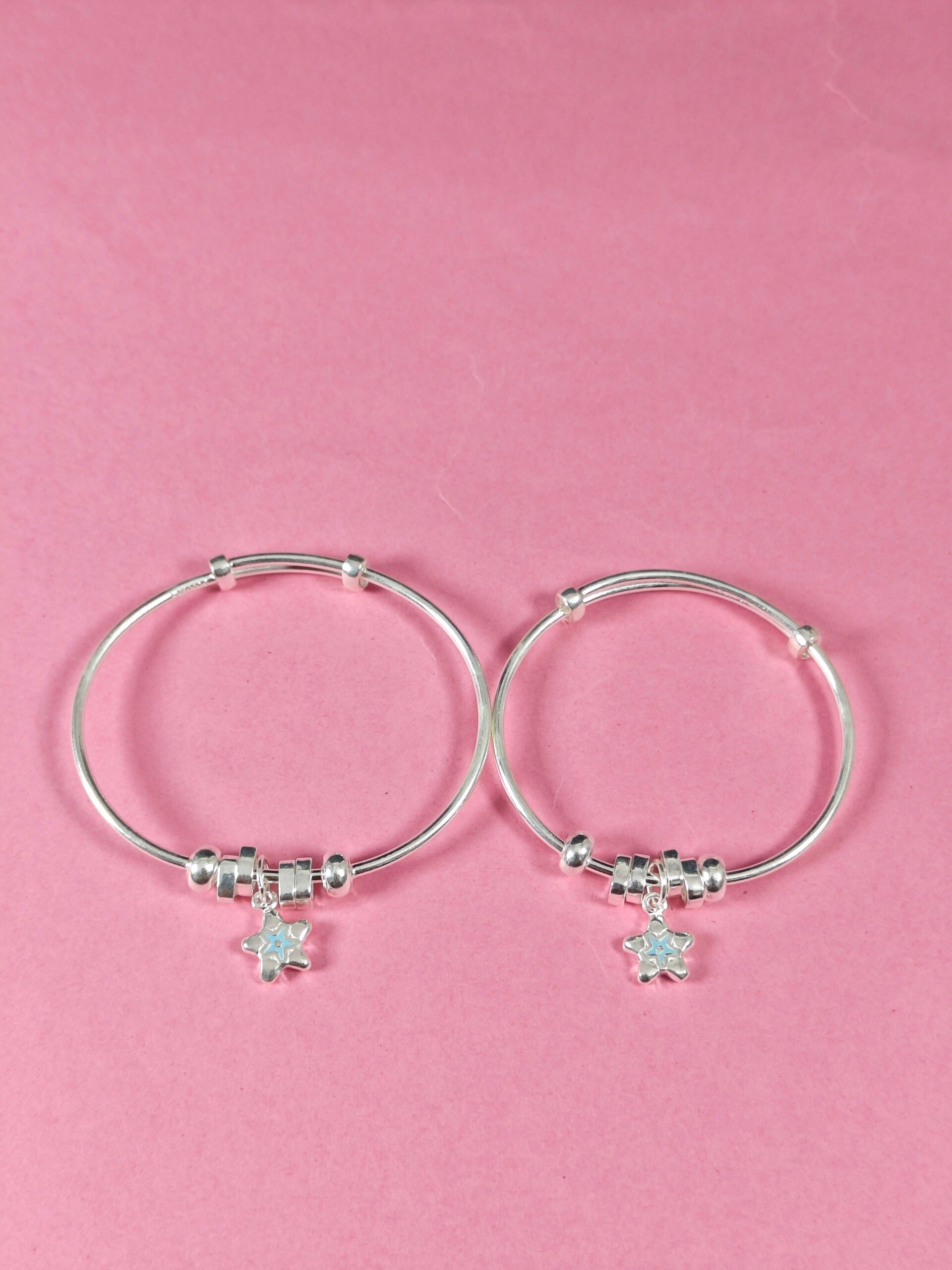 Silver hoop earrings with star charms on a pink background