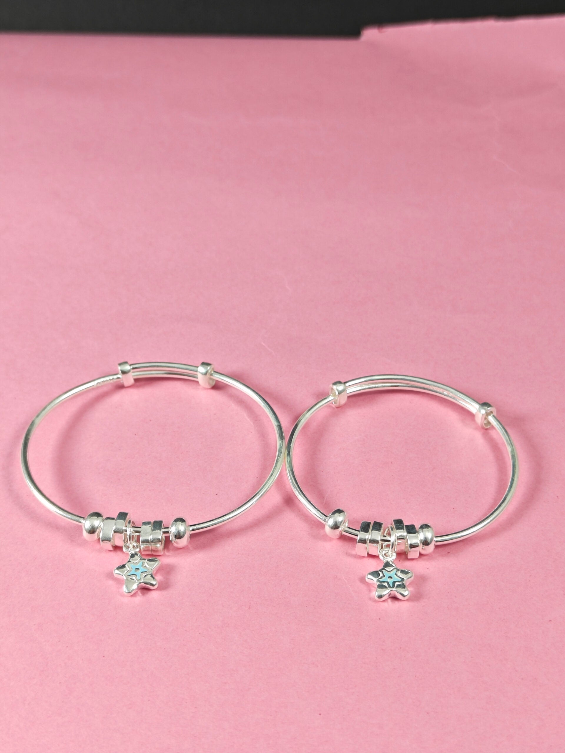 Silver hoop earrings with star-shaped charms on a pink background
