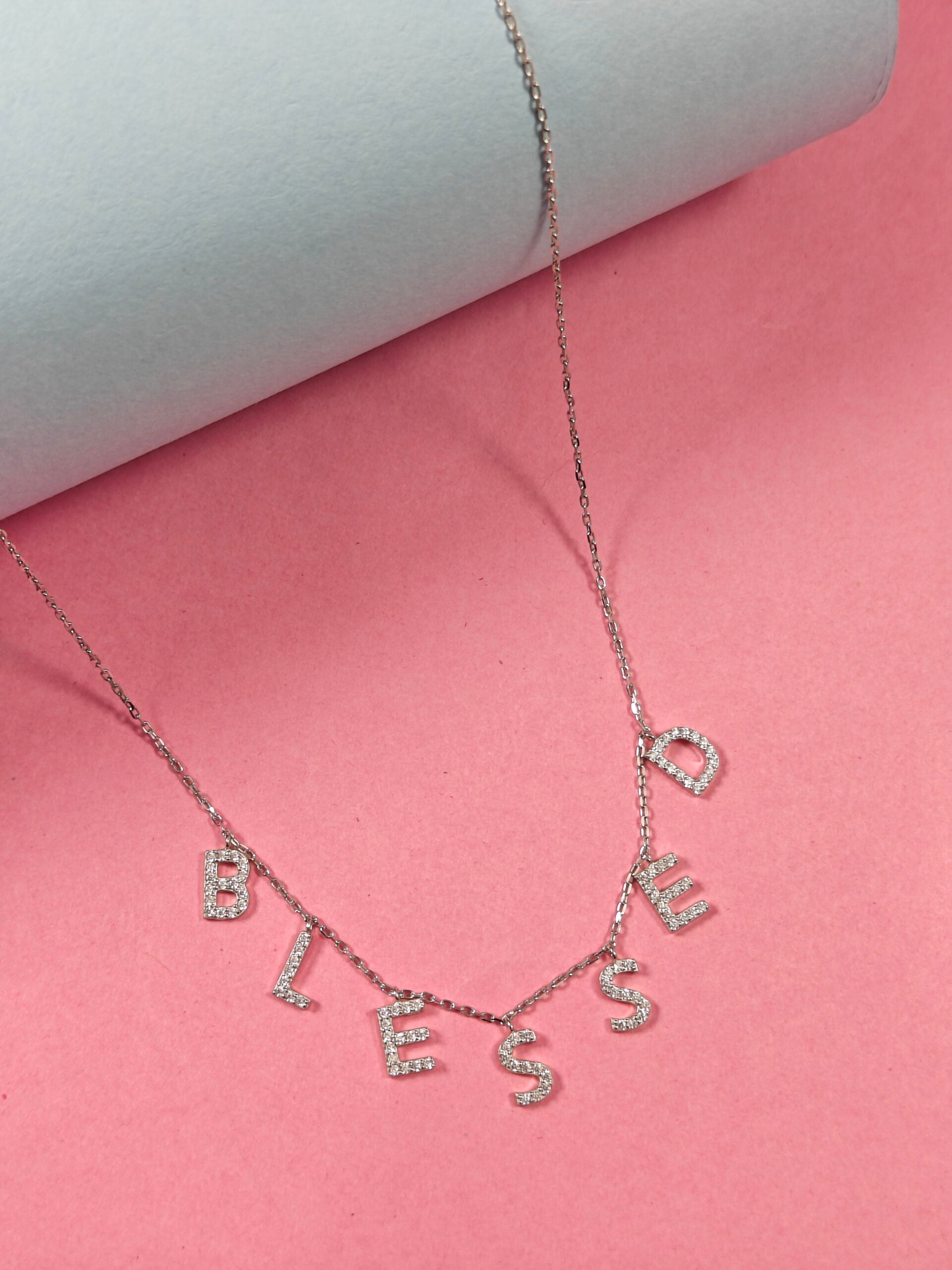 Necklace with 'Blessed' pendant on a pink background