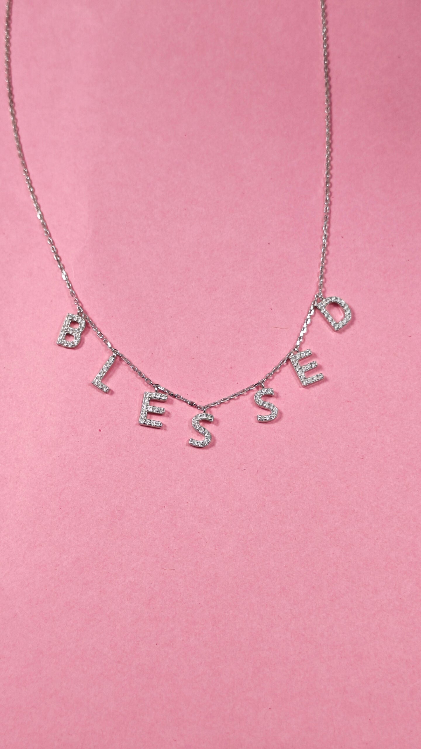 Necklace with 'BLESSED' letters on a pink background