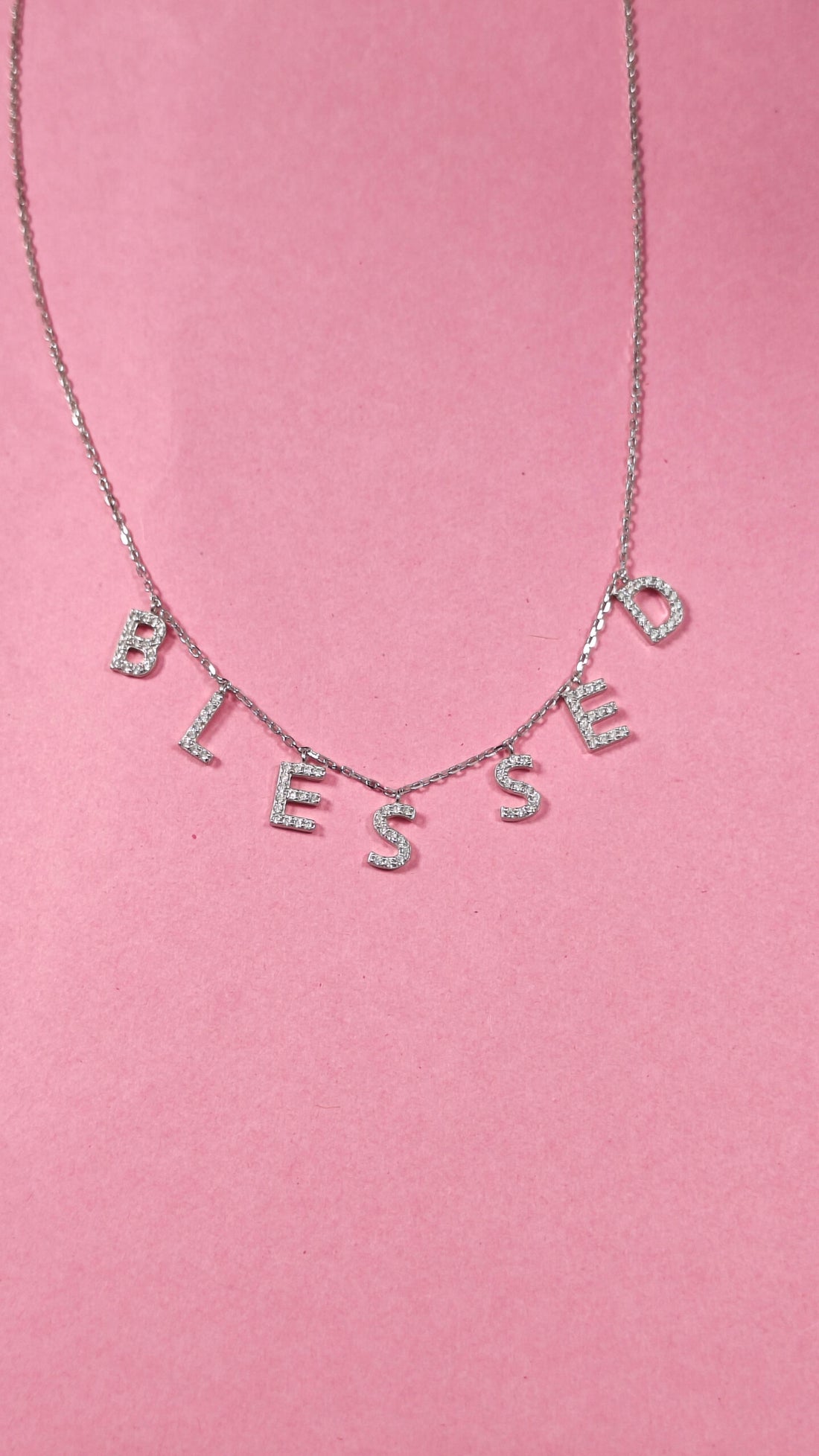 Necklace with 'BLESSED' letters on a pink background