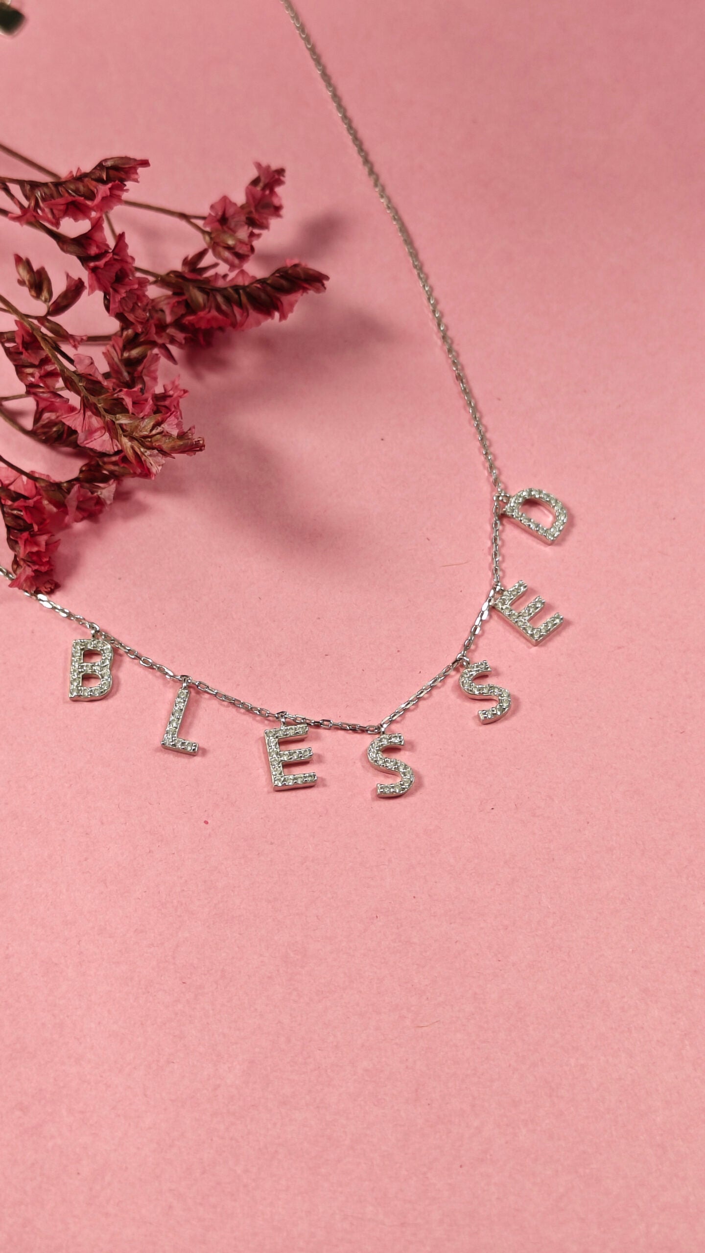 Necklace with 'BLESSED' letters on a pink background