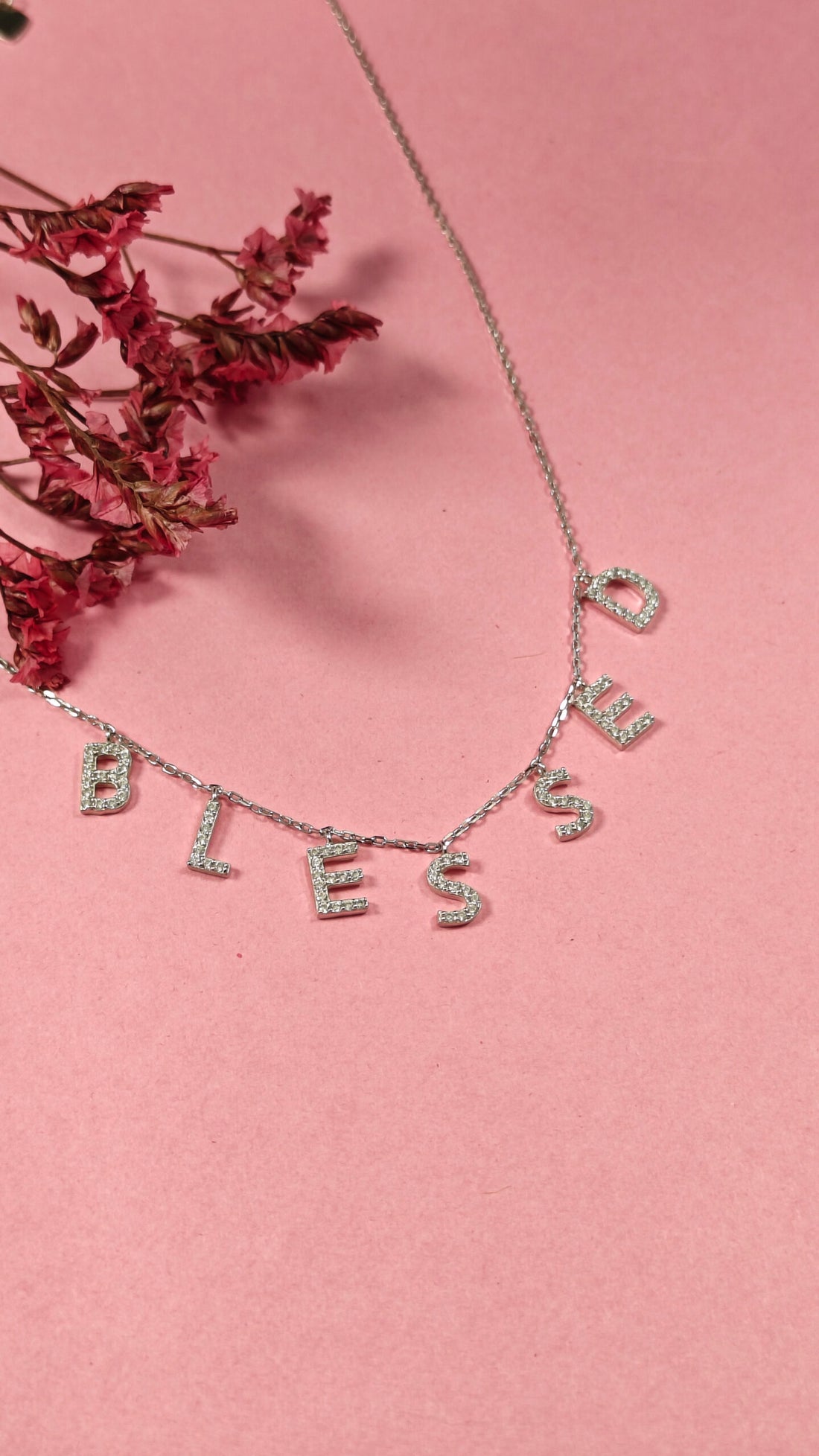 Necklace with 'BLESSED' letters on a pink background
