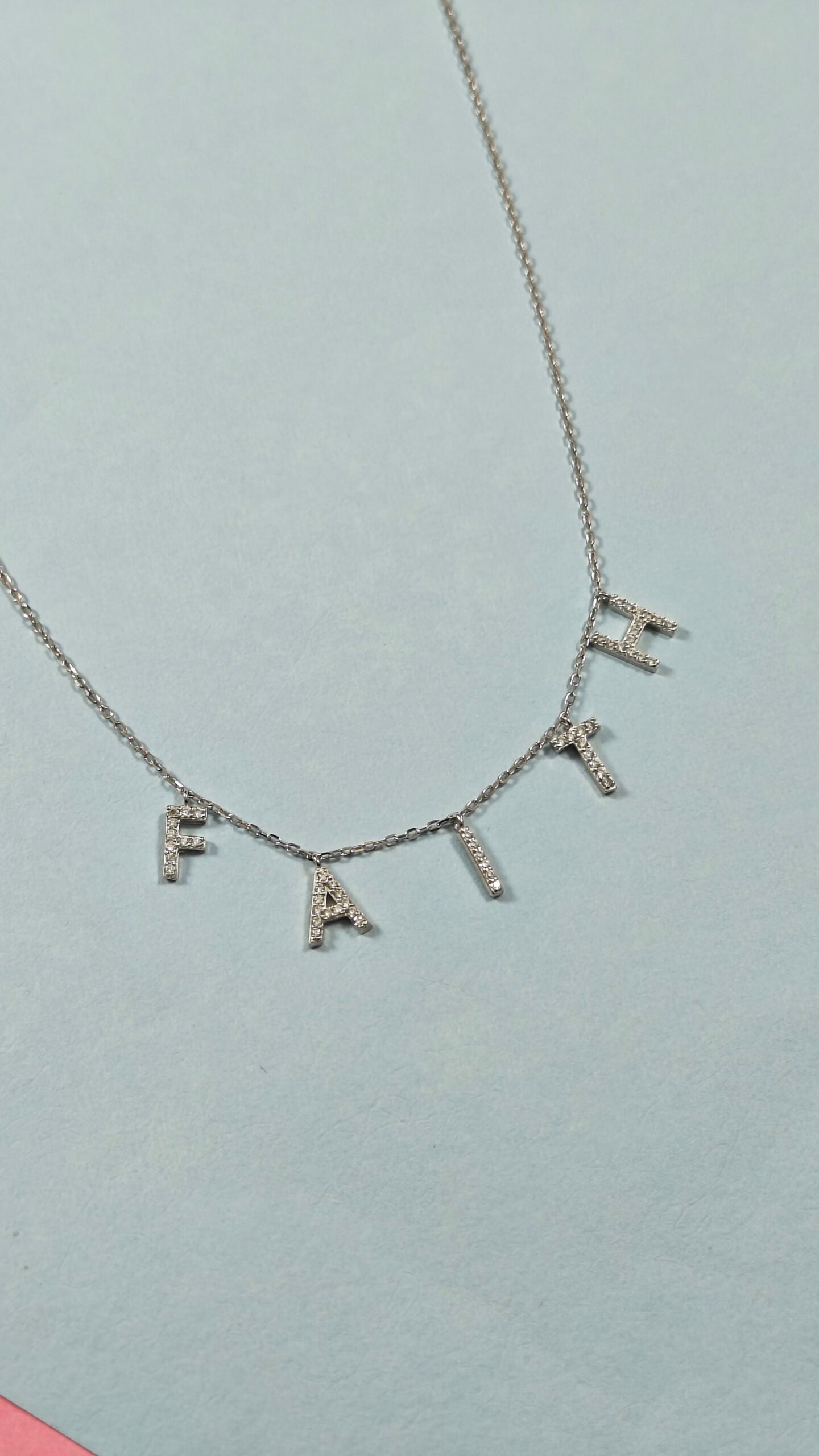 Necklace with 'FAIRE' pendant on a light gray background