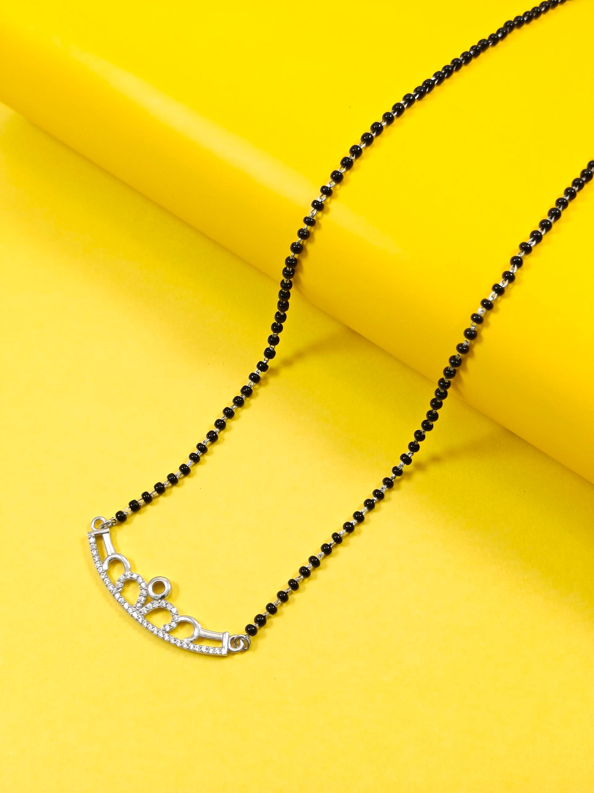 Black beaded necklace with a silver clasp on a yellow background
