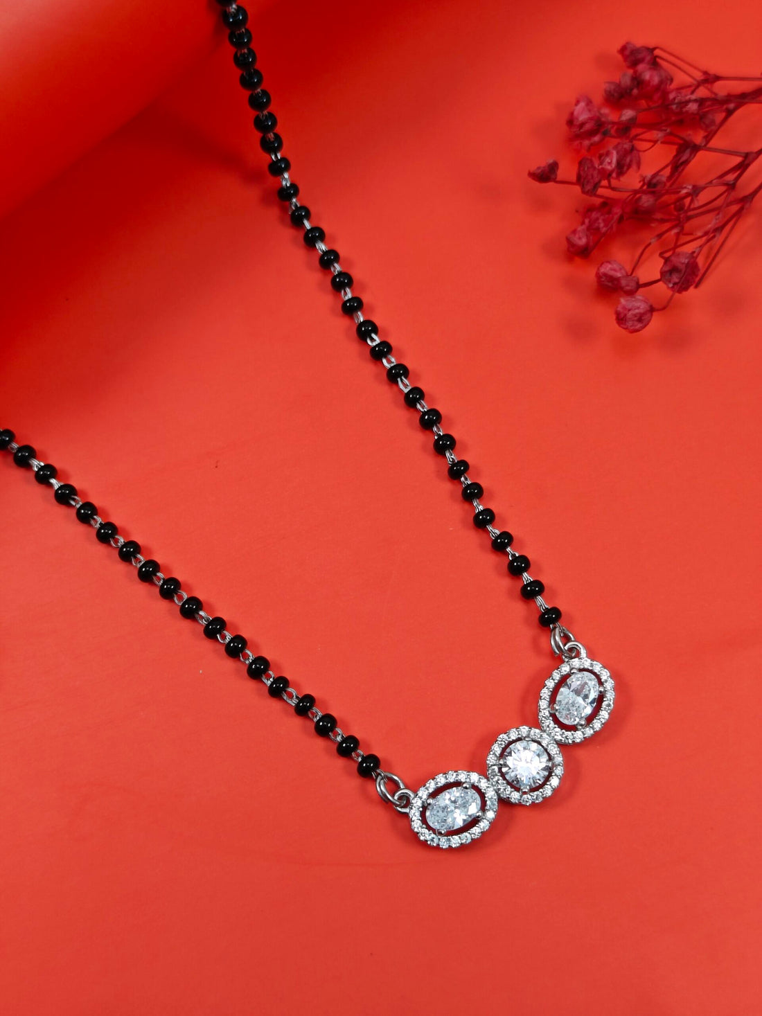 Black beaded necklace with silver clasp on a red background