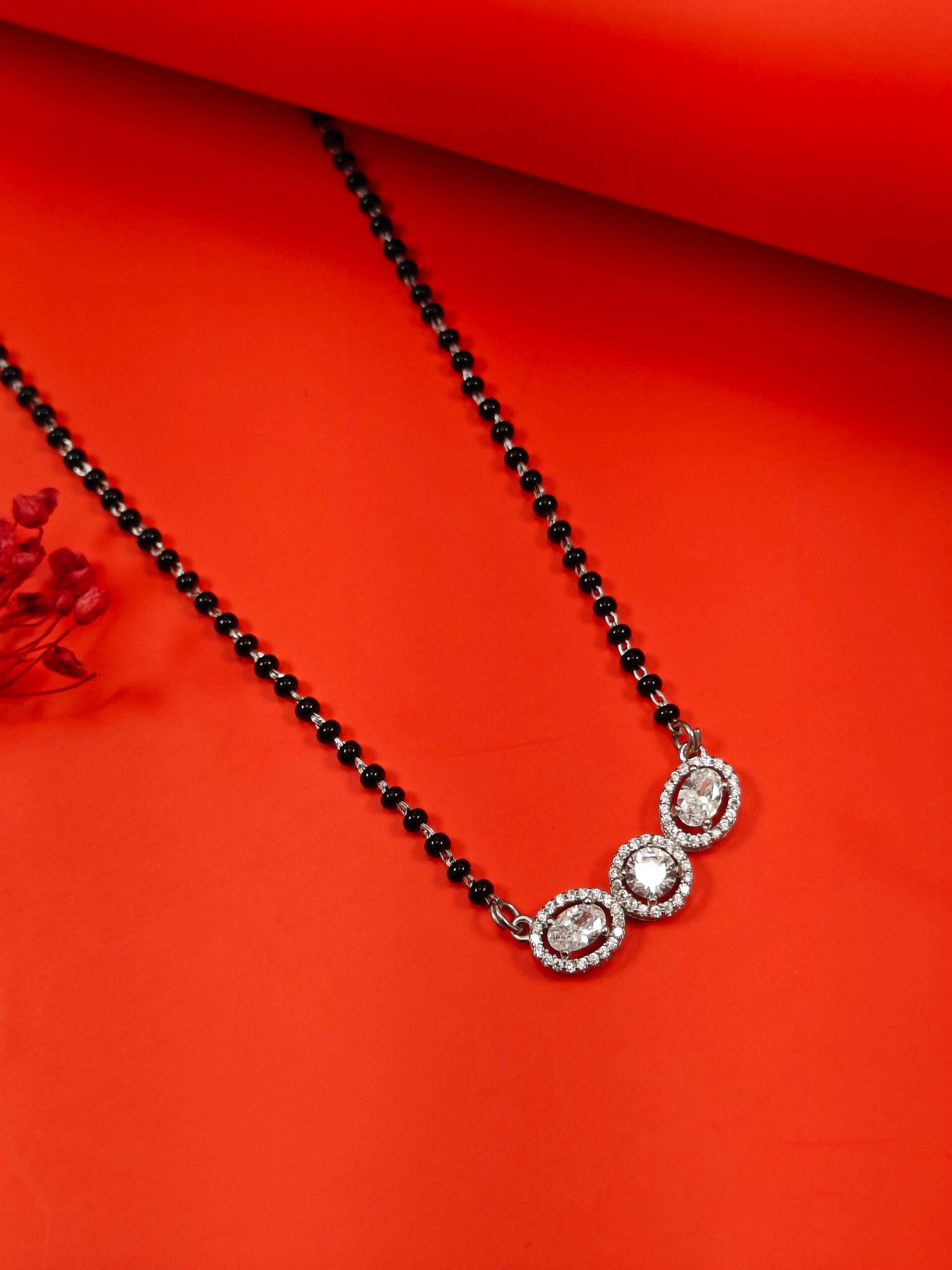 Black beaded necklace with silver pendants on an orange background