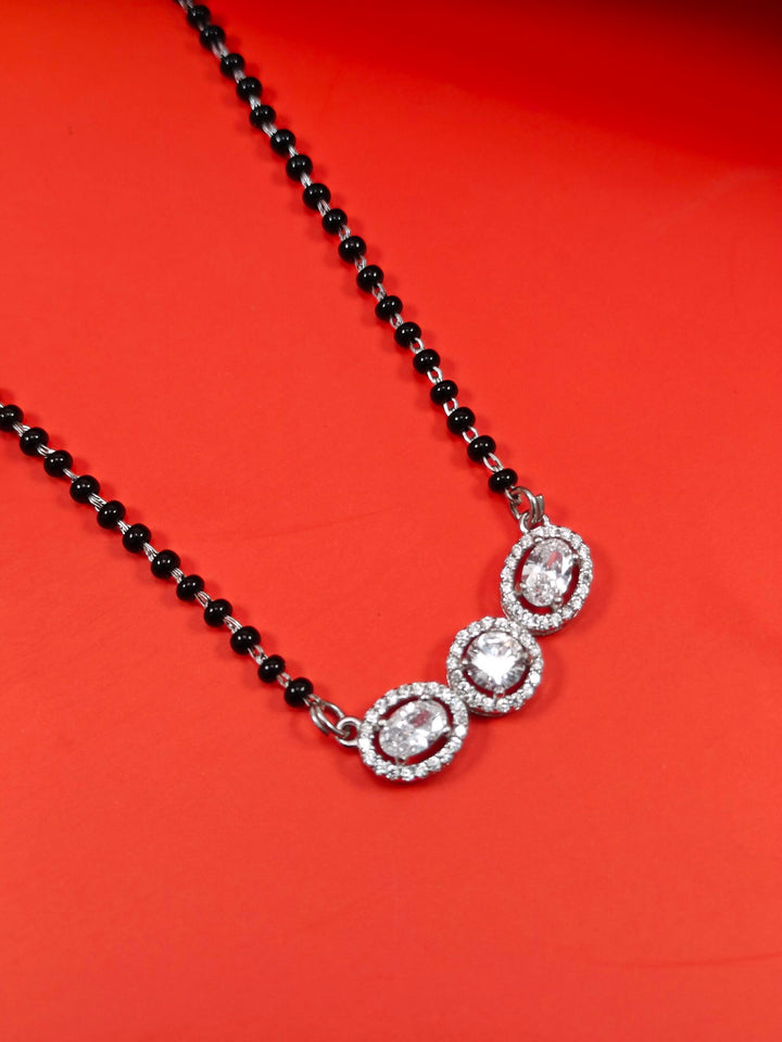Necklace with black beads and silver pendants on a red background