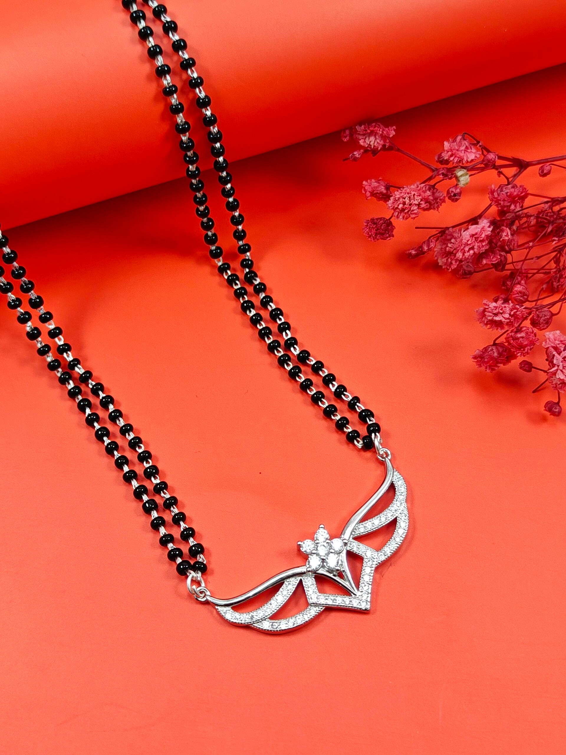 Silver necklace with a black beaded chain on an orange background