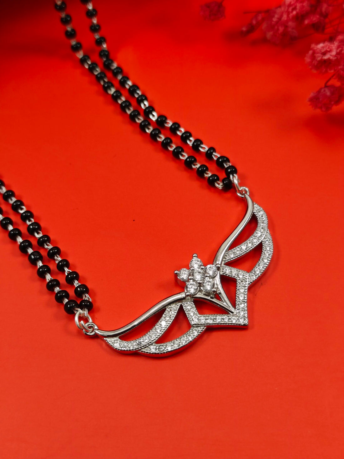 Silver pendant necklace with black beads on a red background