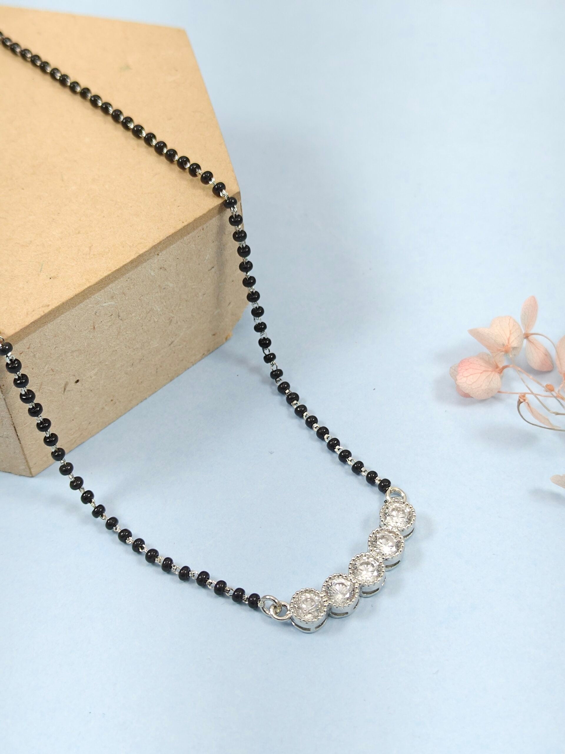 Necklace with black beads and silver clasp on a light blue background