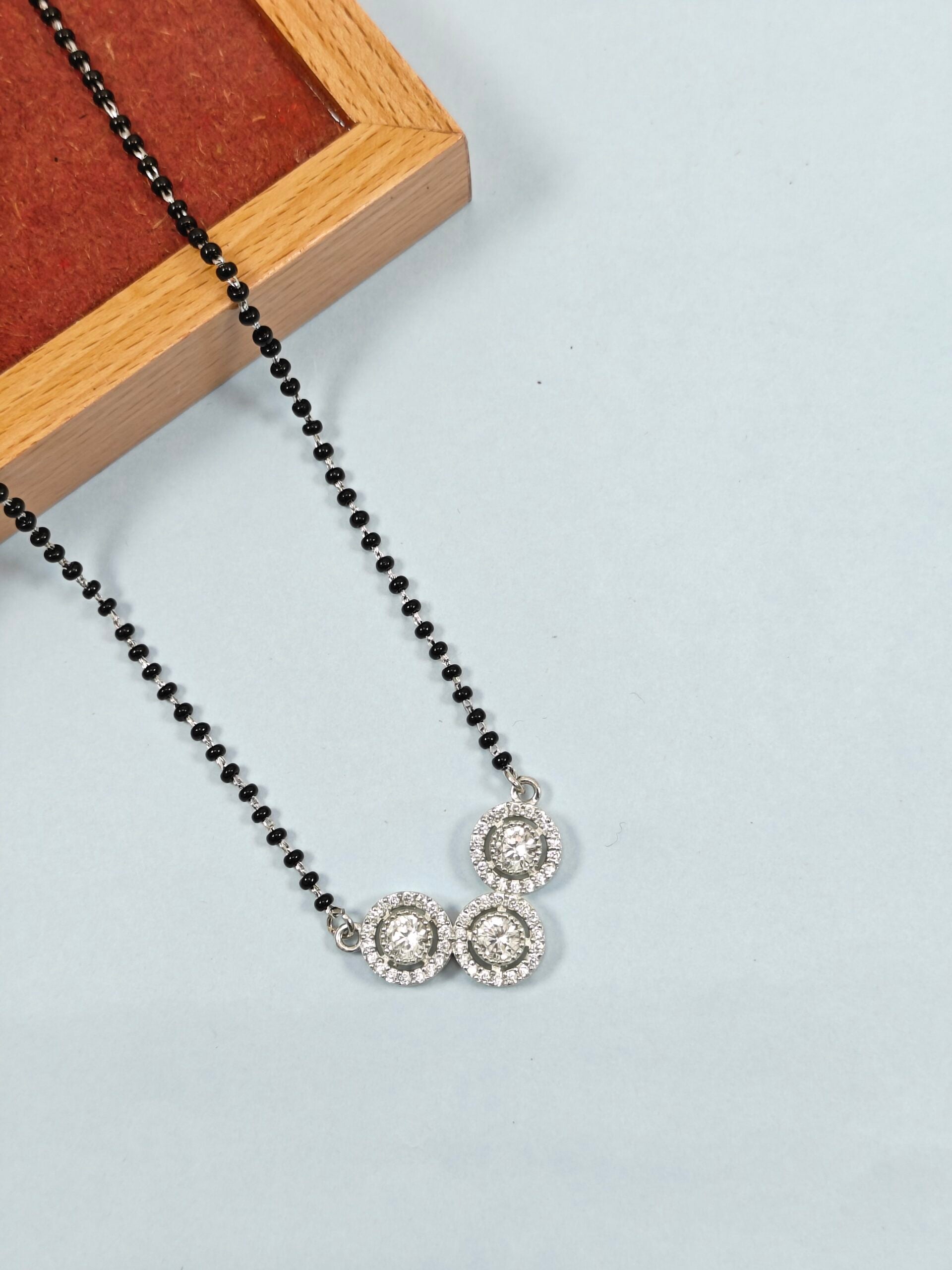 Necklace with black beads and silver pendants on a light gray background