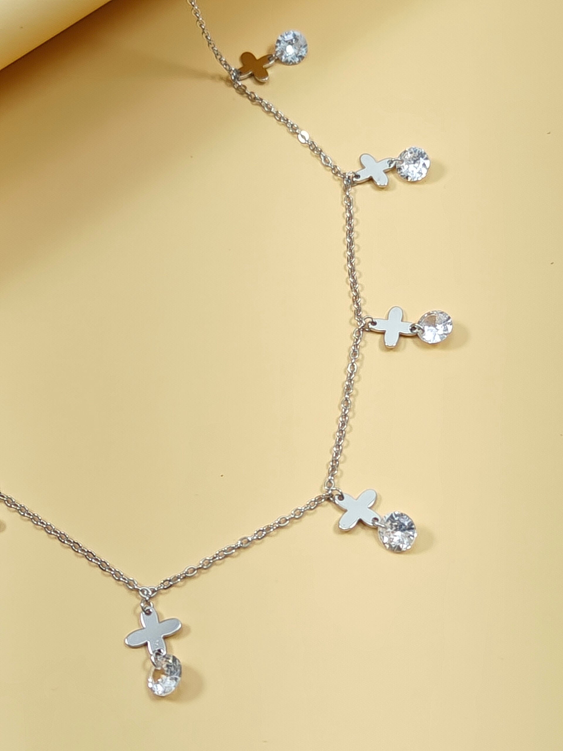 Necklace with cross and heart pendants on a beige background