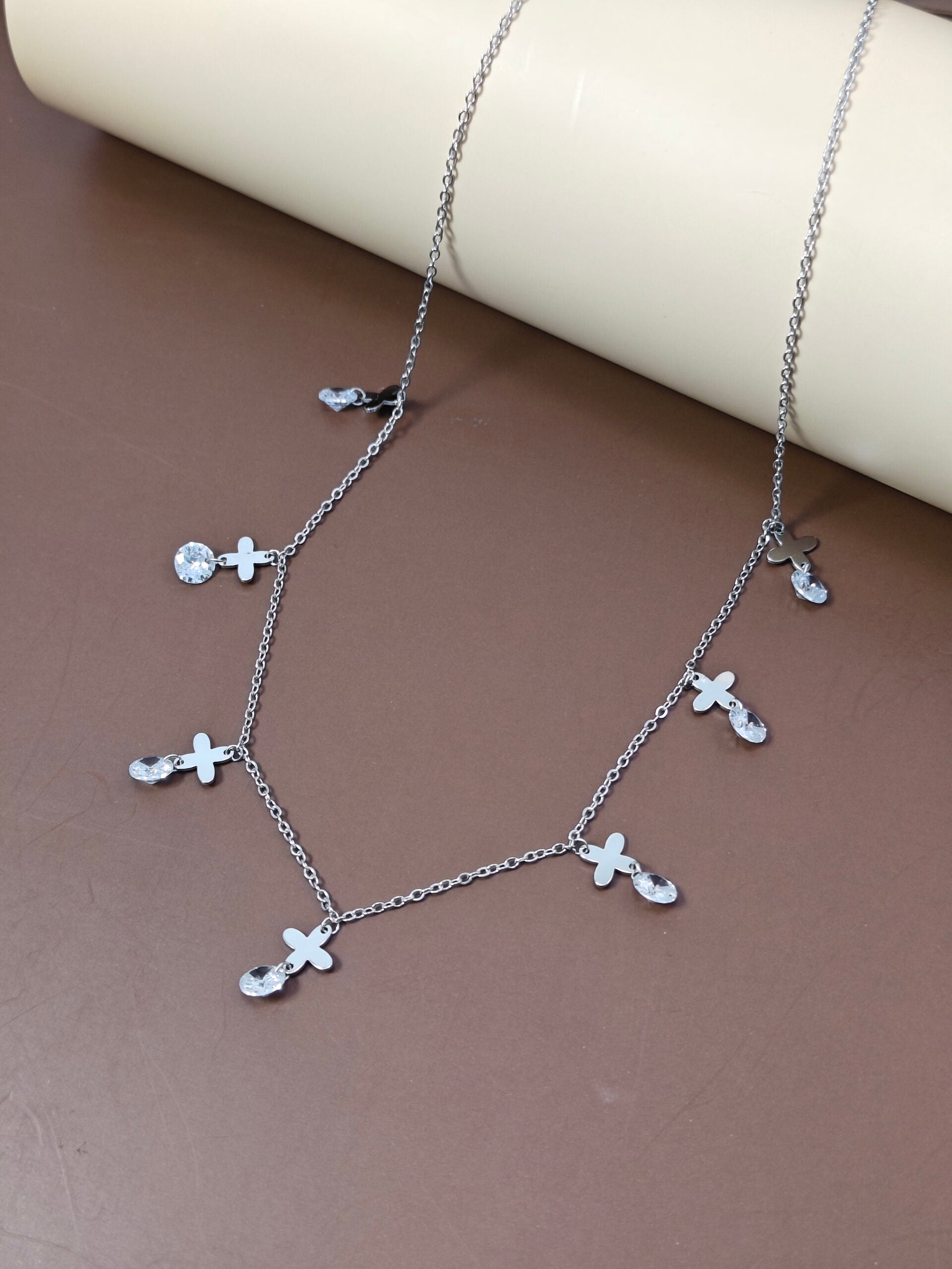 Silver necklace with floral pendants on a brown surface