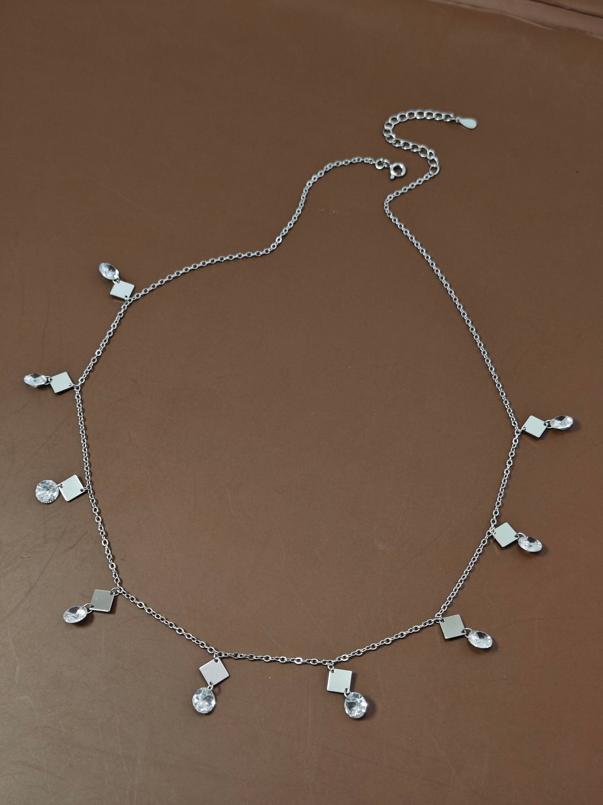 Silver necklace with pendant charms on a brown surface