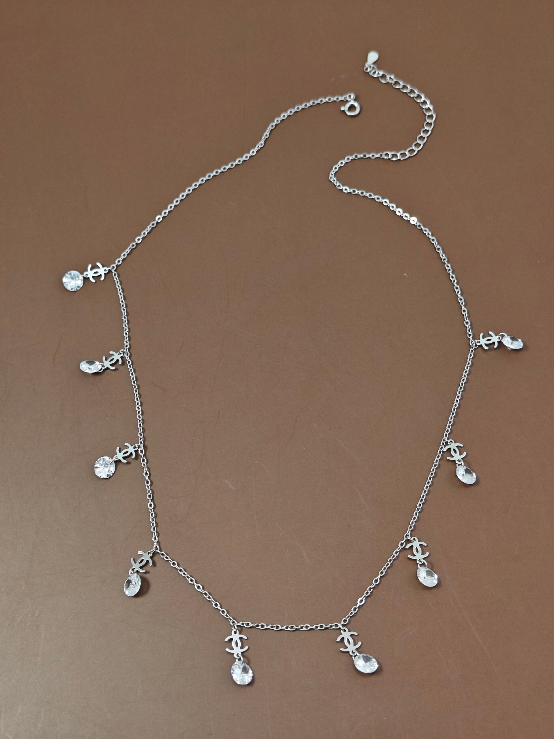 Silver necklace with small charms on a brown background