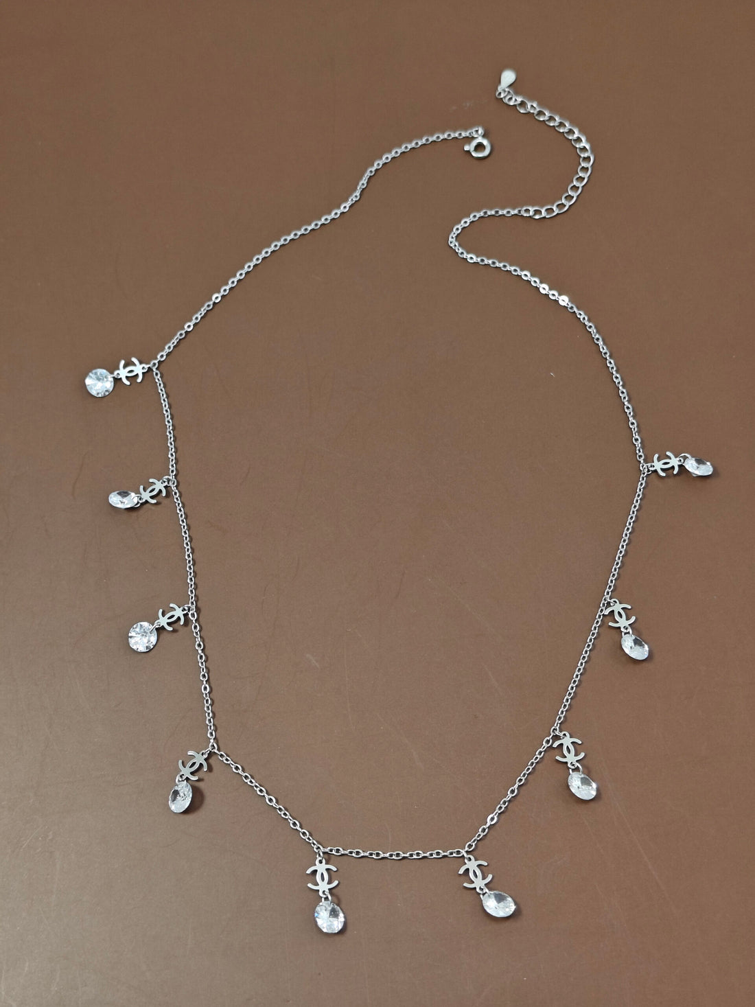 Silver necklace with small charms on a brown background
