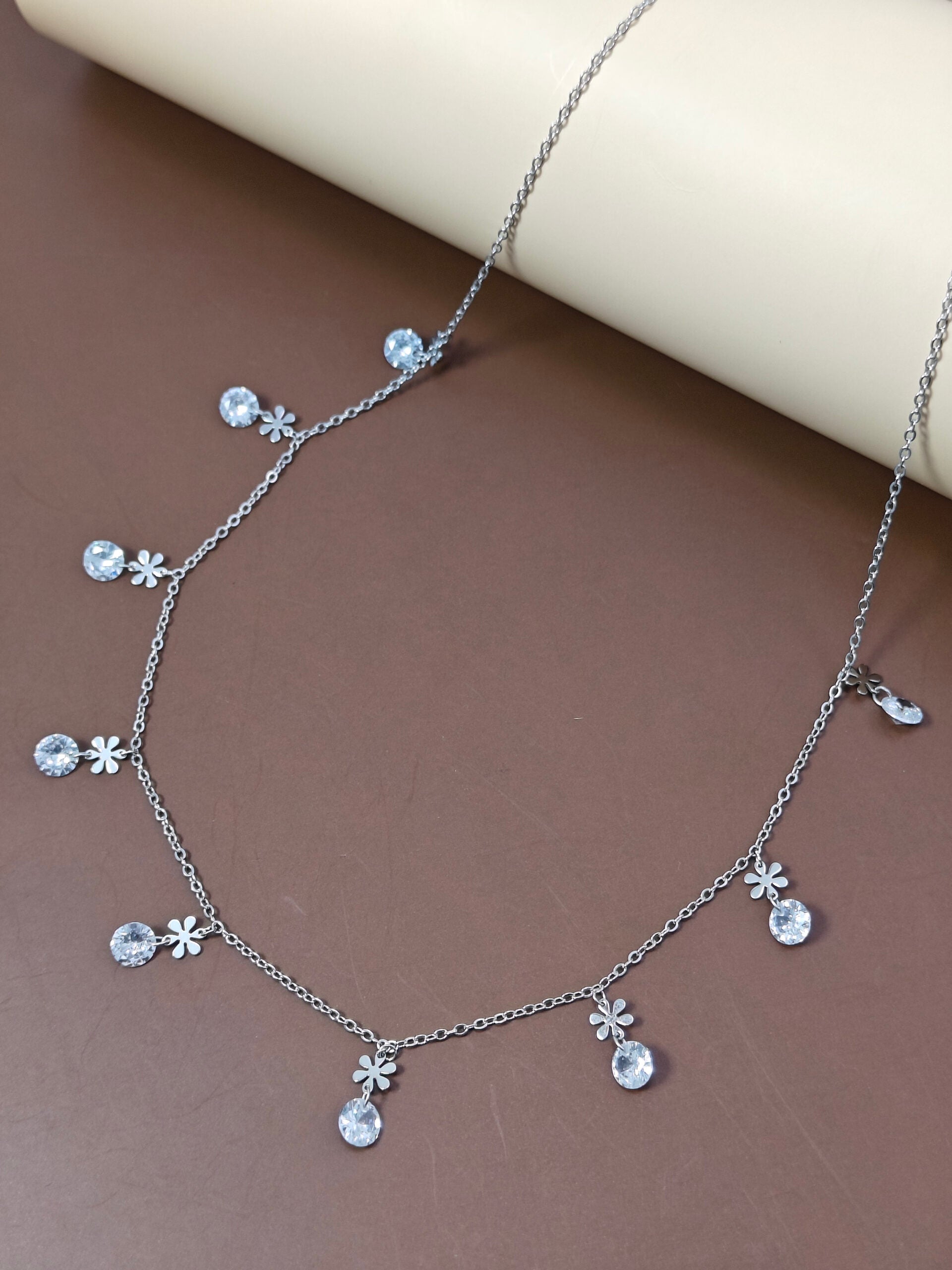 Silver necklace with floral pendants on a brown surface