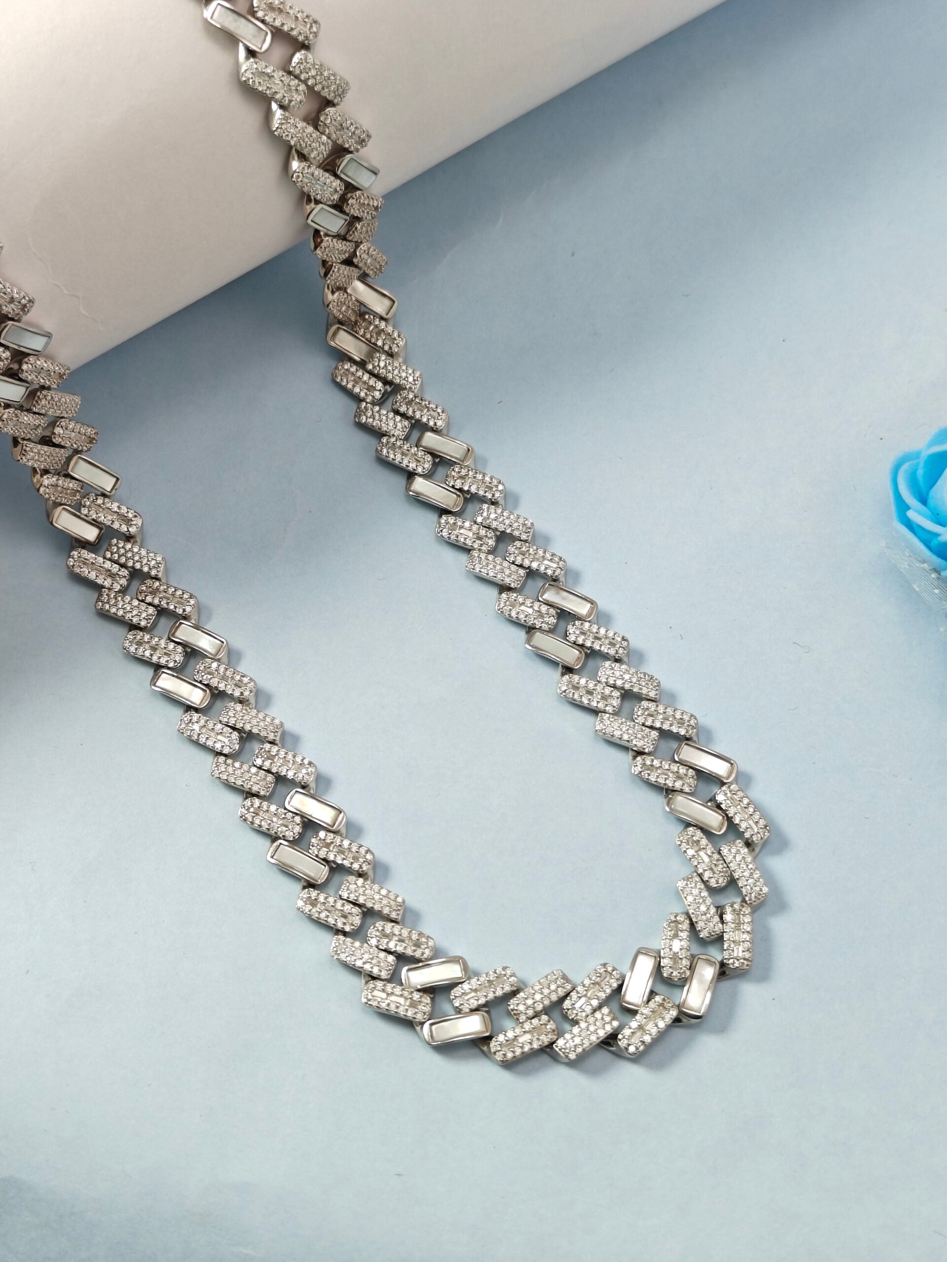 Silver chain necklace on a light blue background
