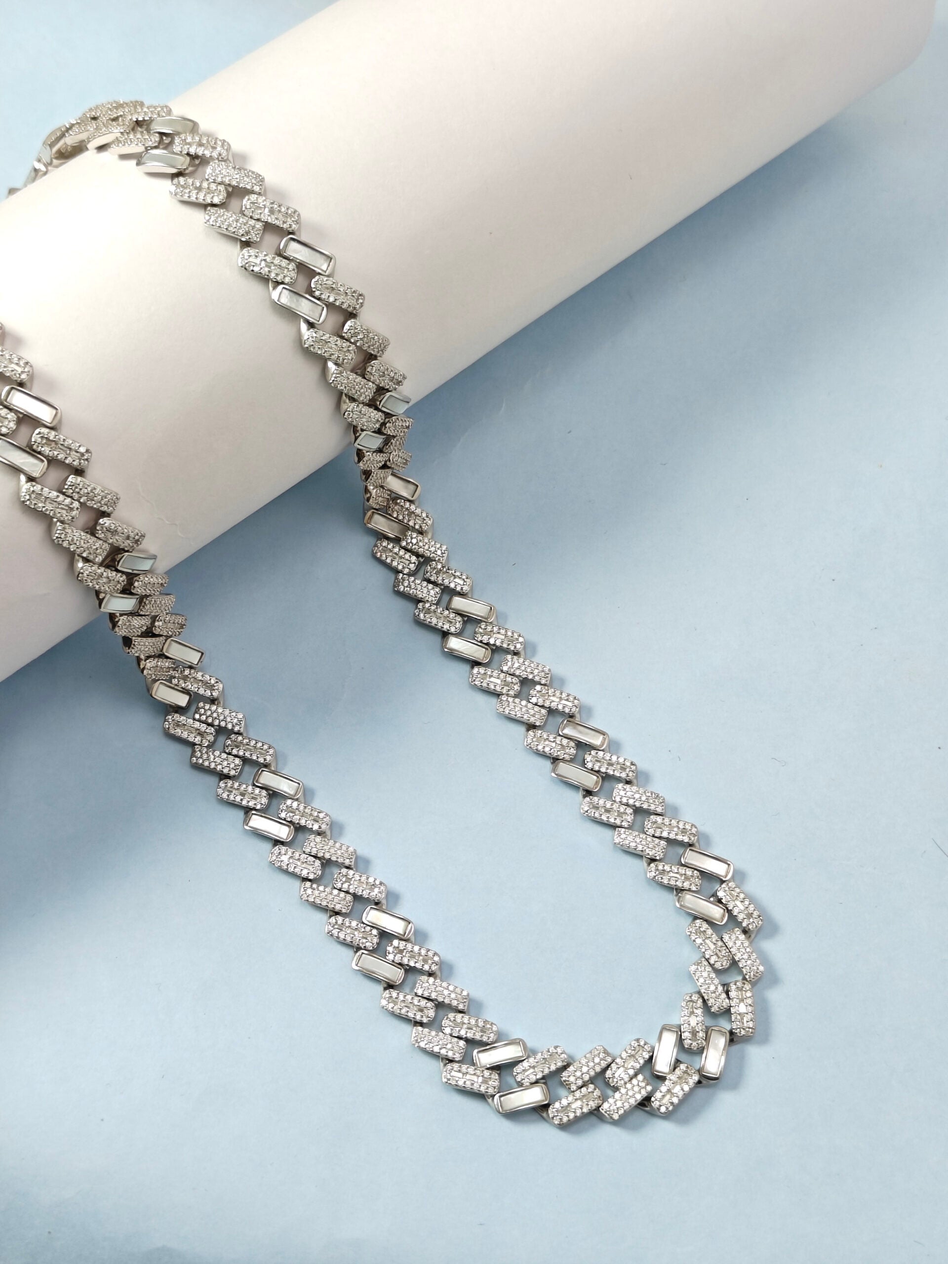 Silver chain necklace on a light blue background