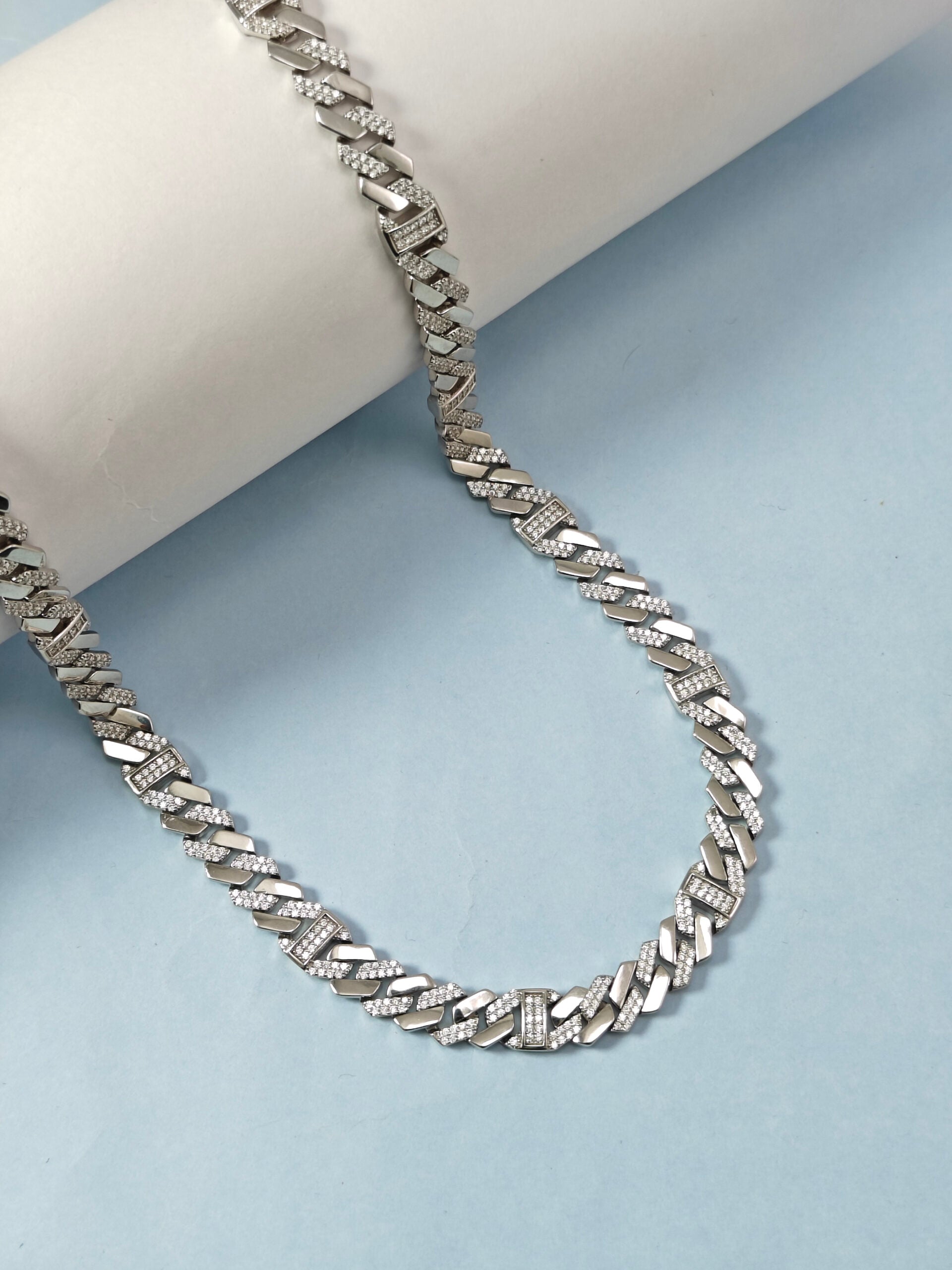 Silver chain necklace on a light blue background