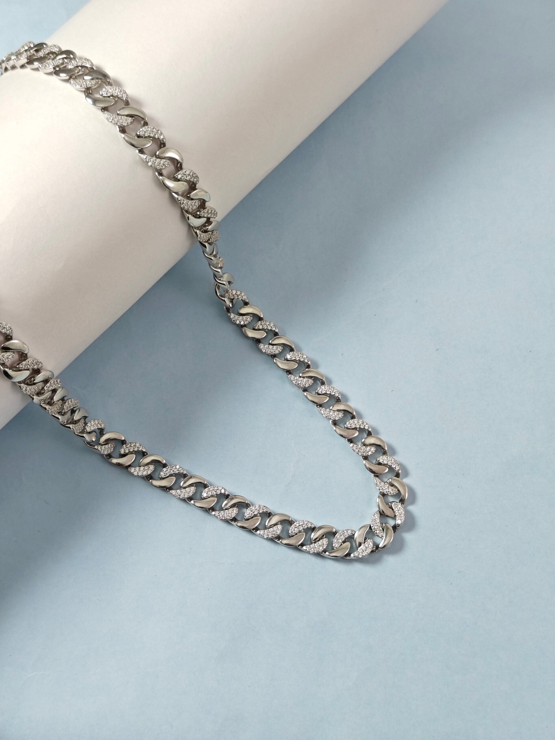 Silver chain necklace on a light blue background