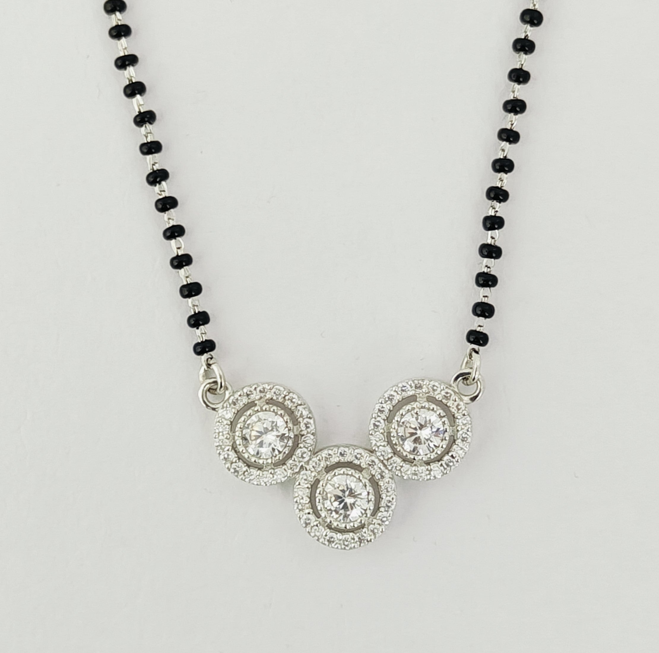 Necklace with black beaded chain and silver circular pendants on a light gray background