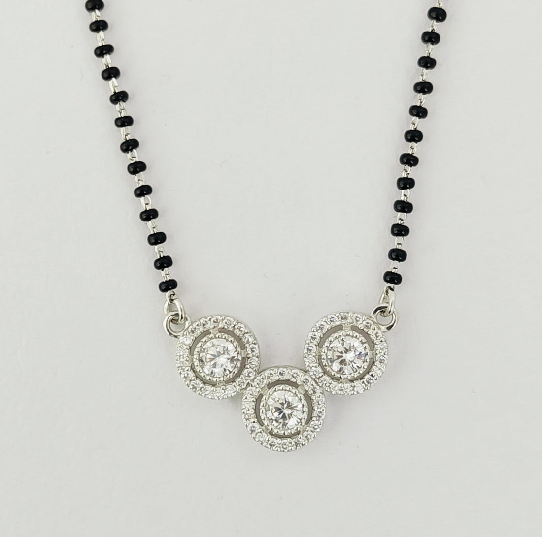 Necklace with black beaded chain and silver circular pendants on a light gray background