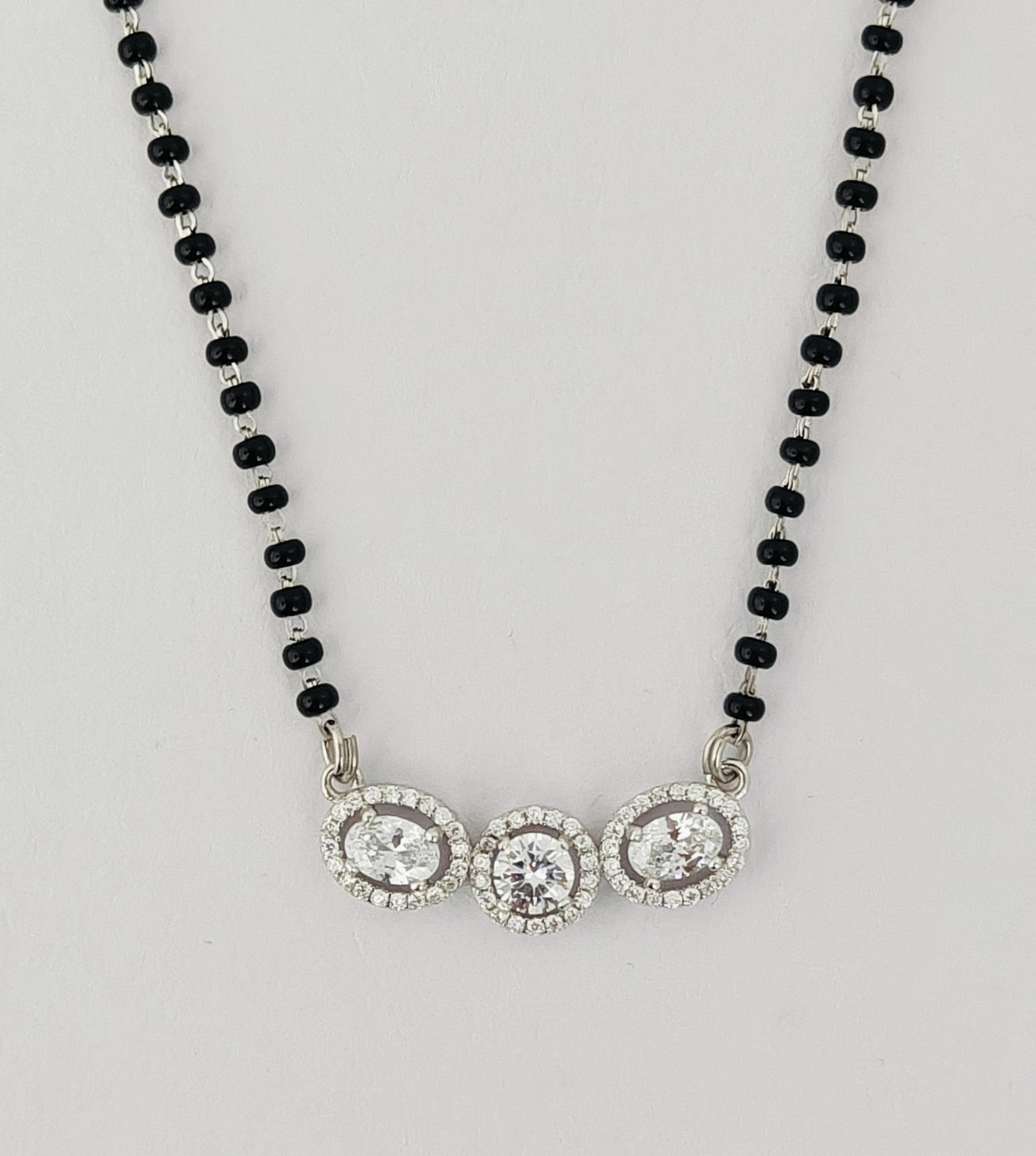 Necklace with black beads and silver clasp on a light gray background
