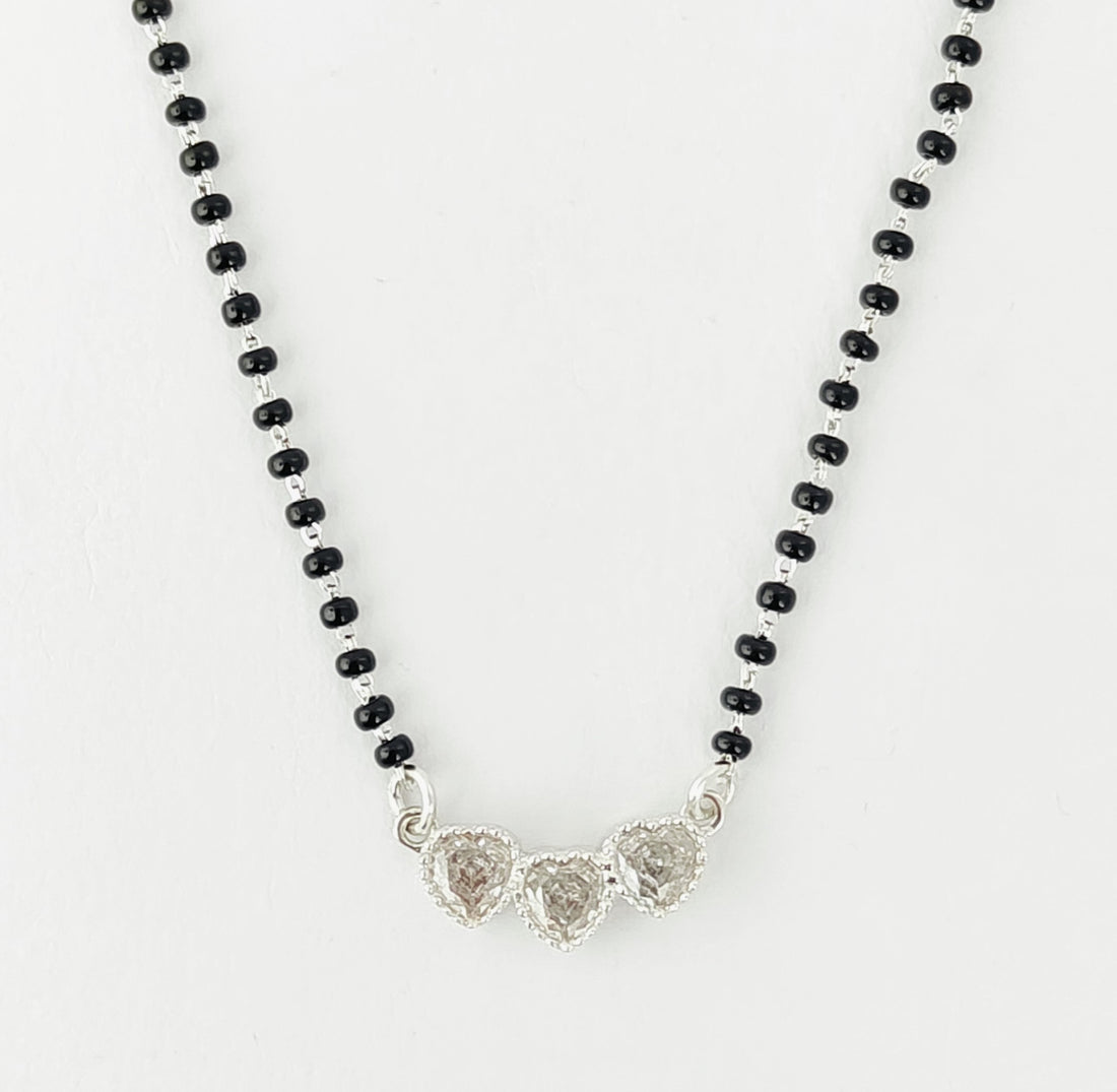 Necklace with black beads and silver heart-shaped pendants on a white background