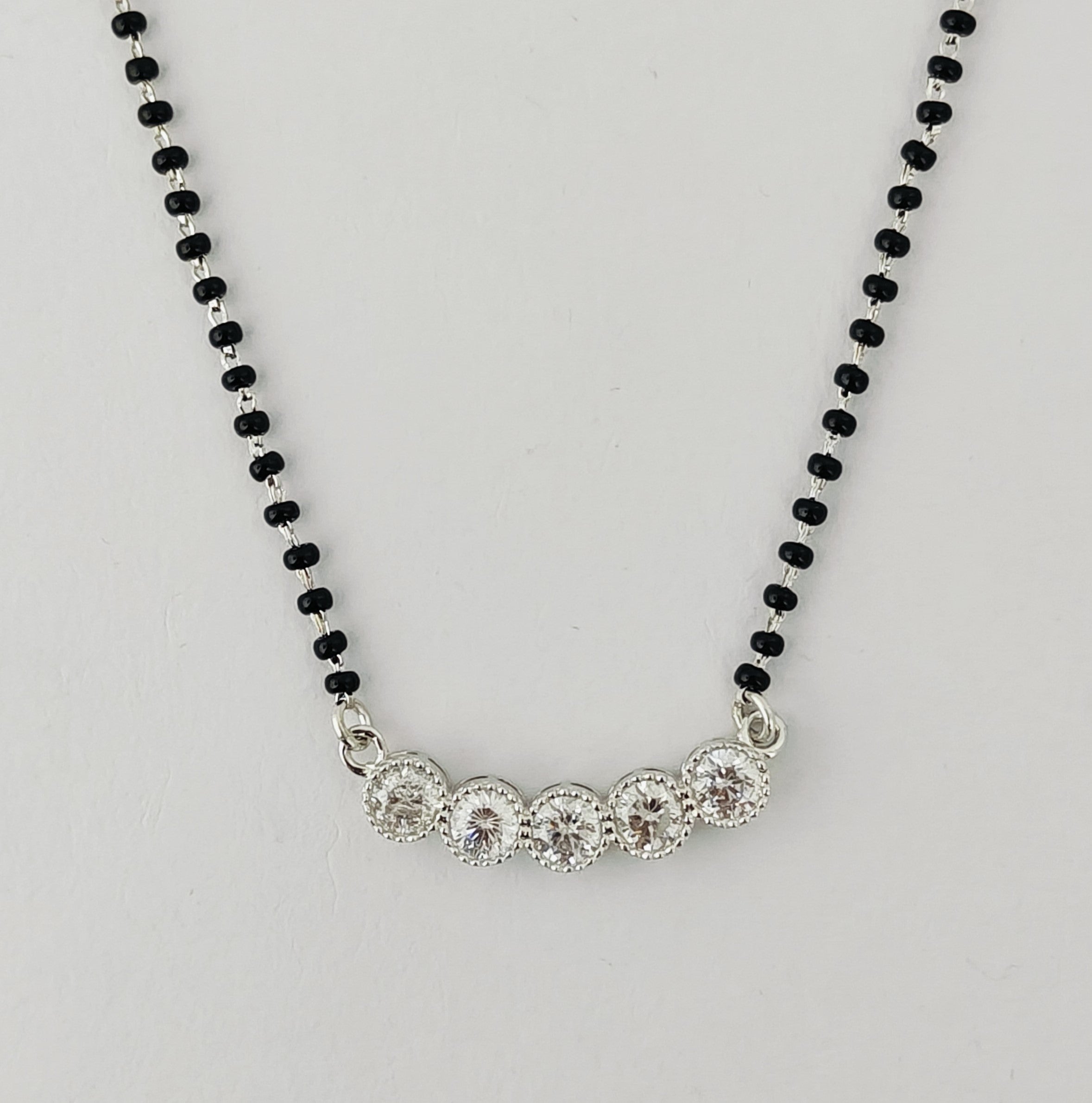 Necklace with black beaded chain and silver clasp on a light gray background