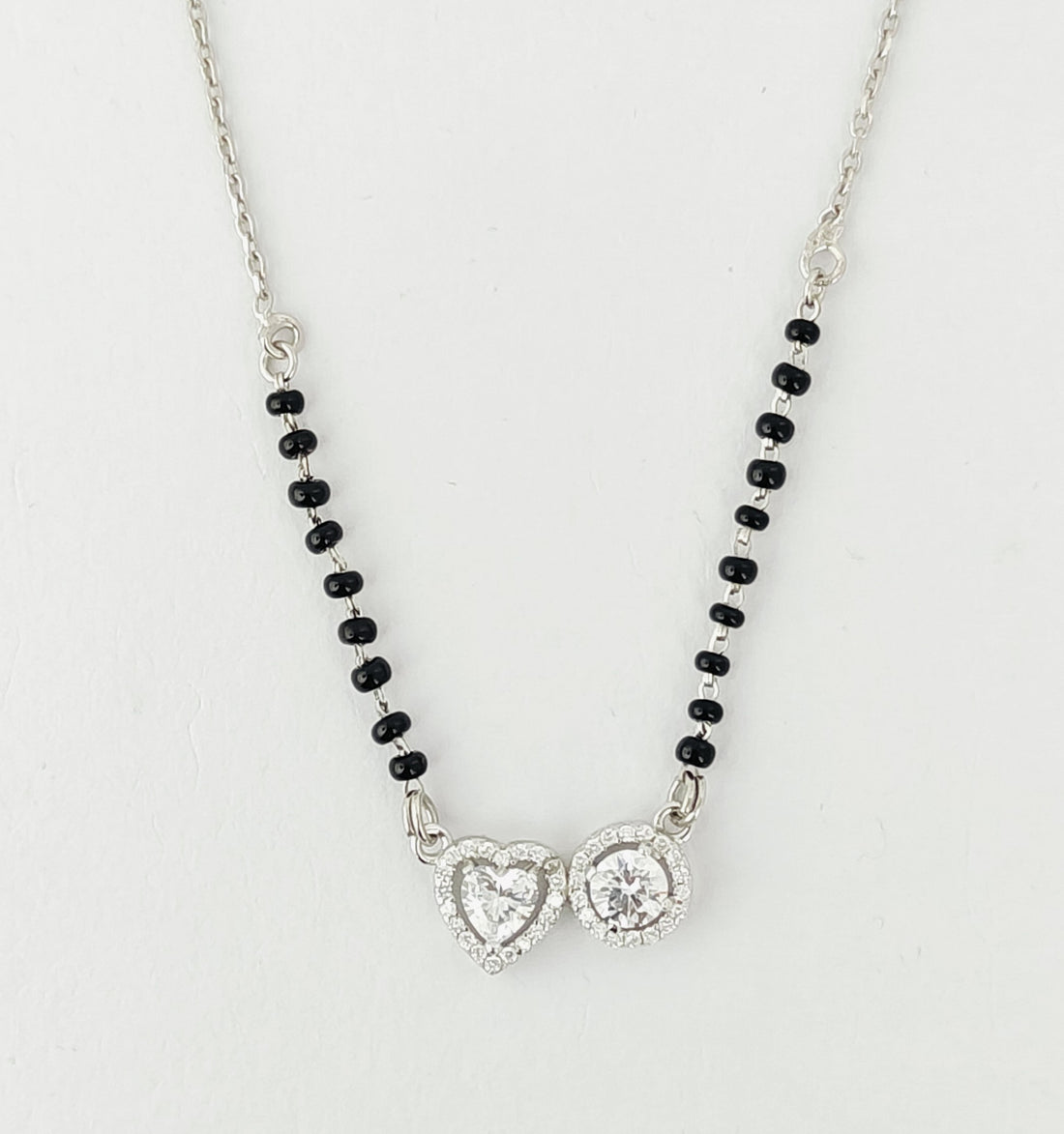 Necklace with heart-shaped pendants and black beads on a light gray background