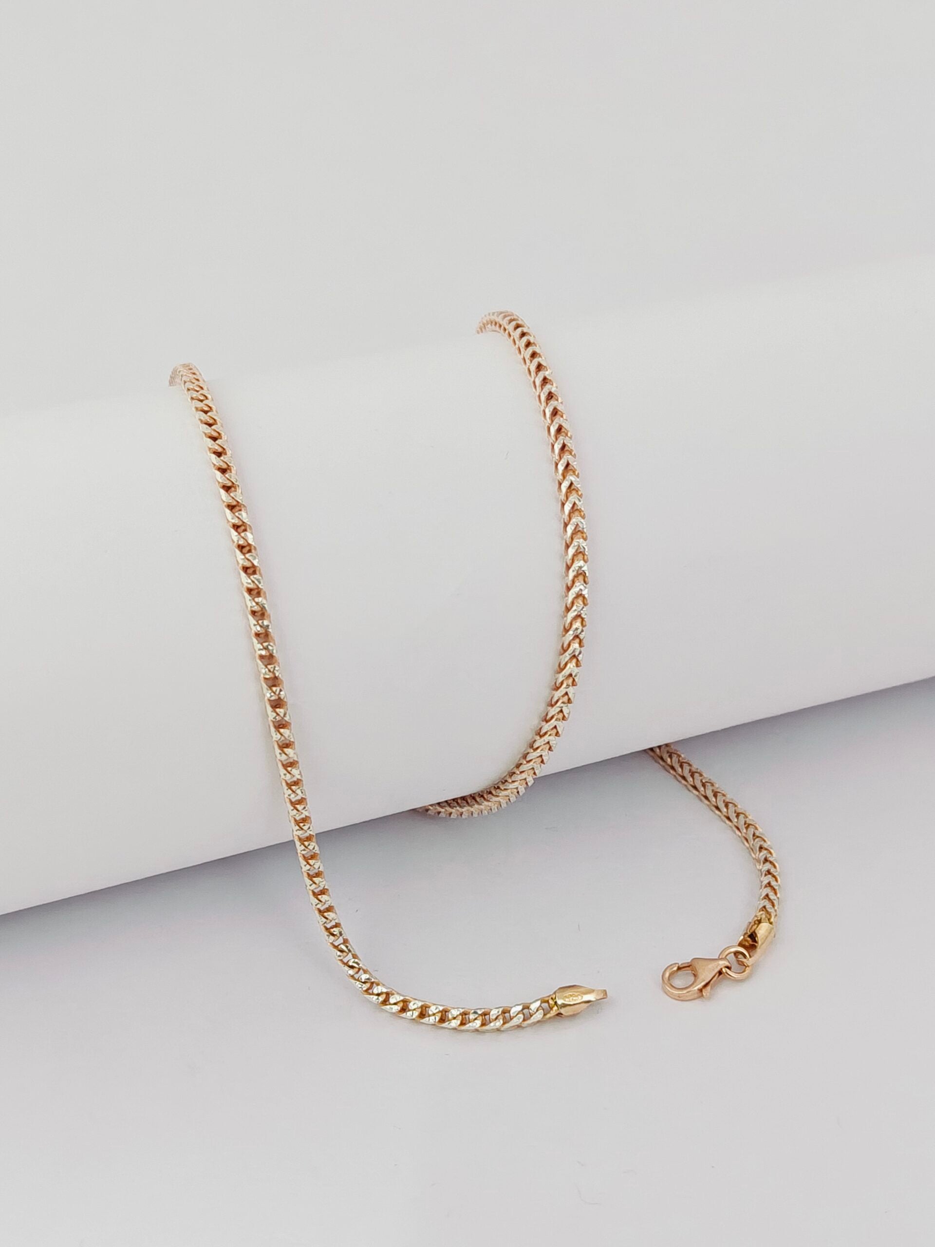 Gold chain necklace on a light gray surface
