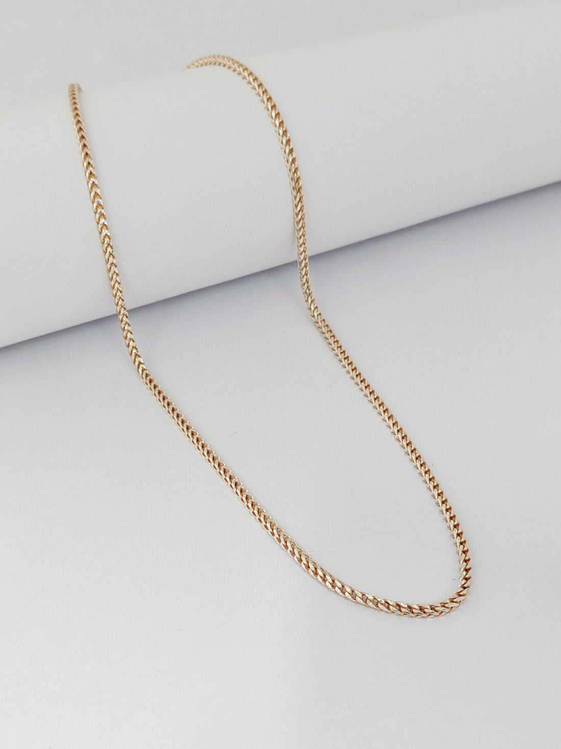 Gold chain necklace on a light gray background