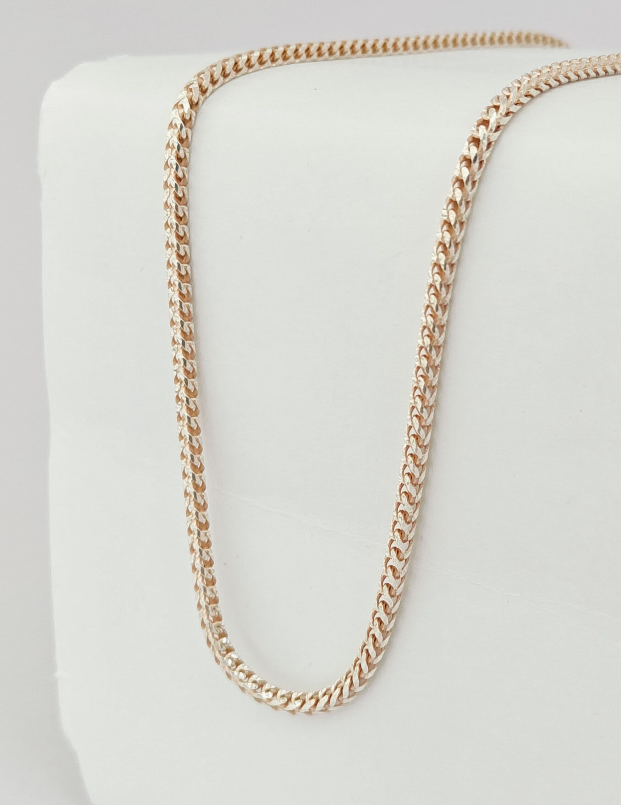 Gold chain necklace on a white cushion