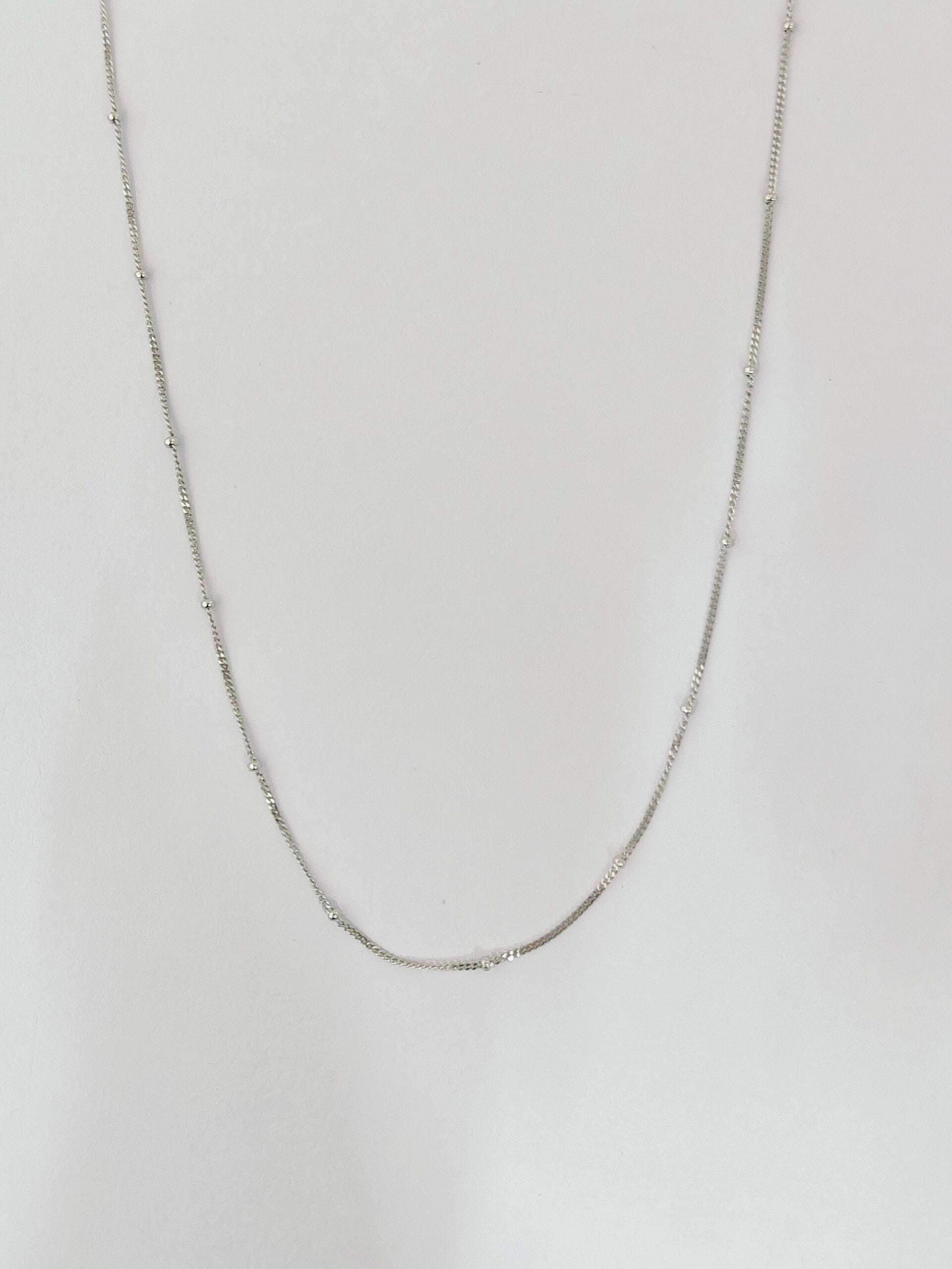 Silver chain necklace on a light gray background