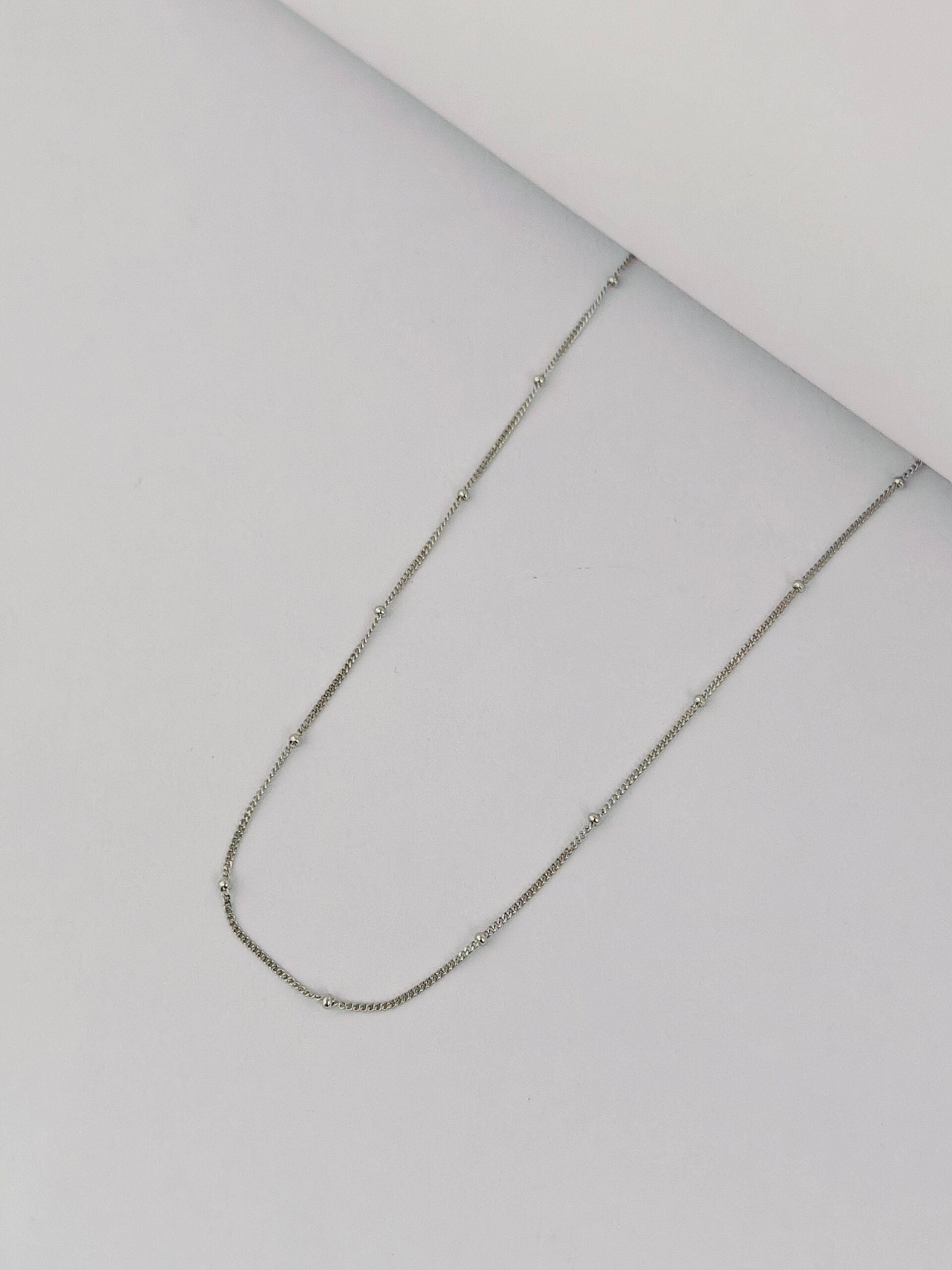 Silver chain necklace on a light gray background