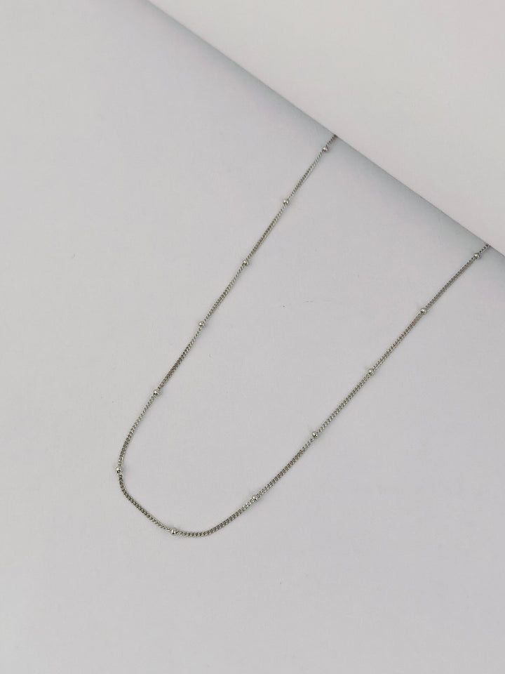 Silver chain necklace on a light gray background