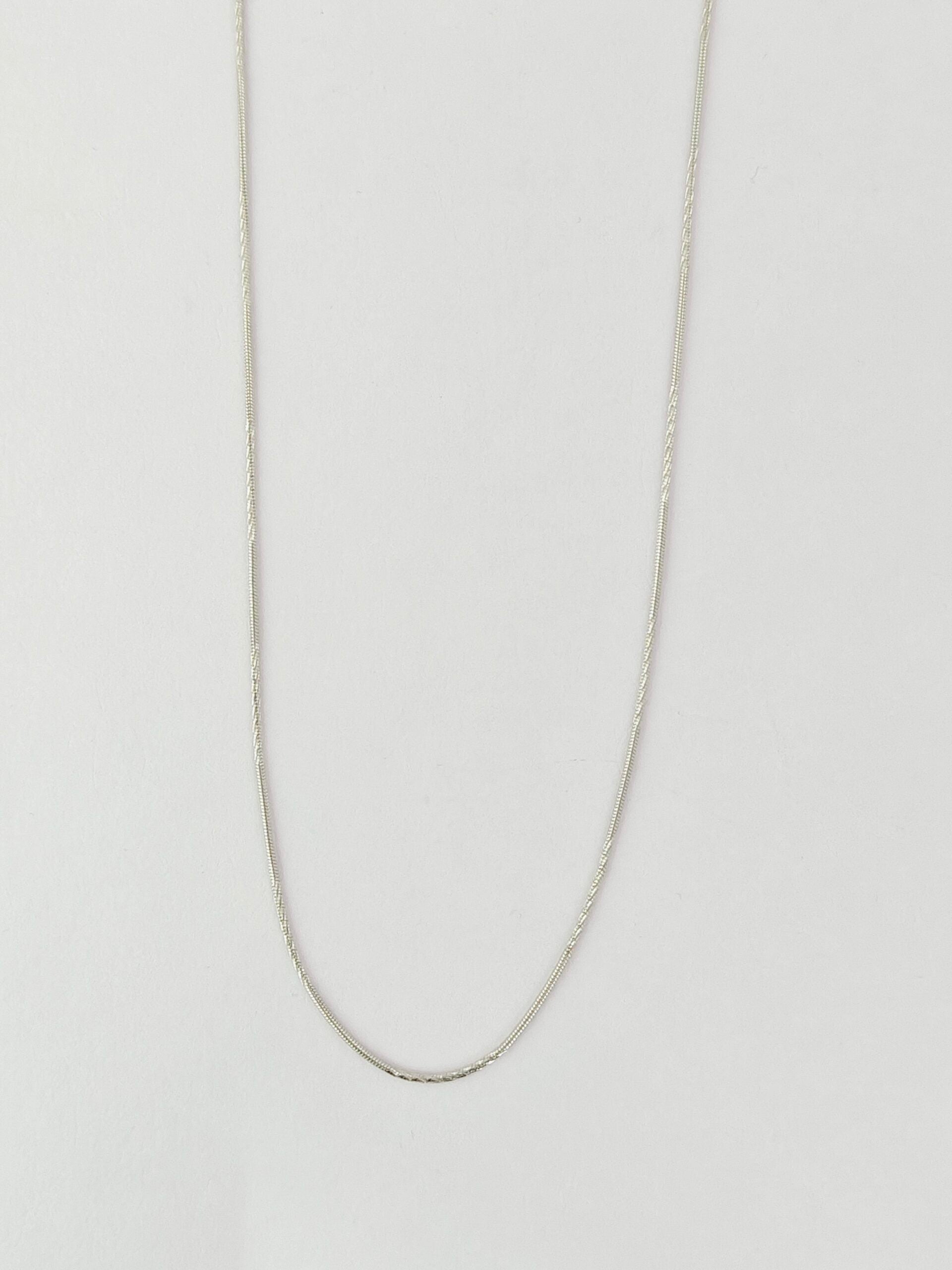 Silver chain necklace on a light gray background